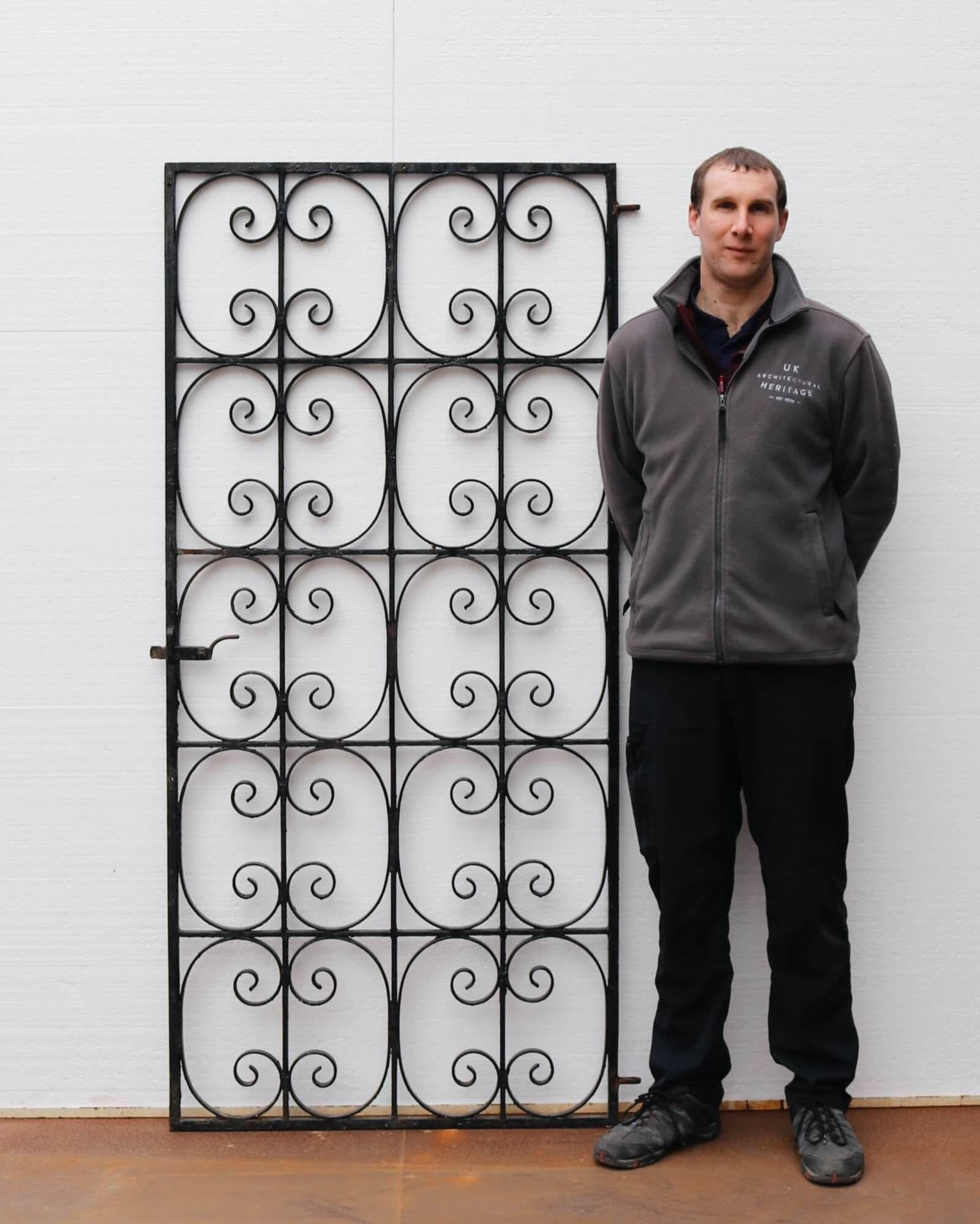 A tall reclaimed Mid-Century Modern wrought iron side gate dating from the 1930s. Detailed with a repeated scrolling pattern, this gate brings elegance and security to a property, perfect for a narrow side passage or scenic garden archway surrounded
