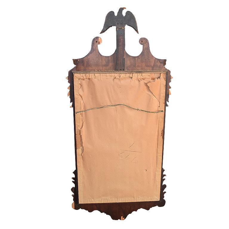 A tall rectangular Federal admiral eagle mirror with gilt details. This wonderful wall mirror has a metal hanging wire at the back for easy installation. It is created from dark stained wood and has scalloped edges. A small thin gold frame accents