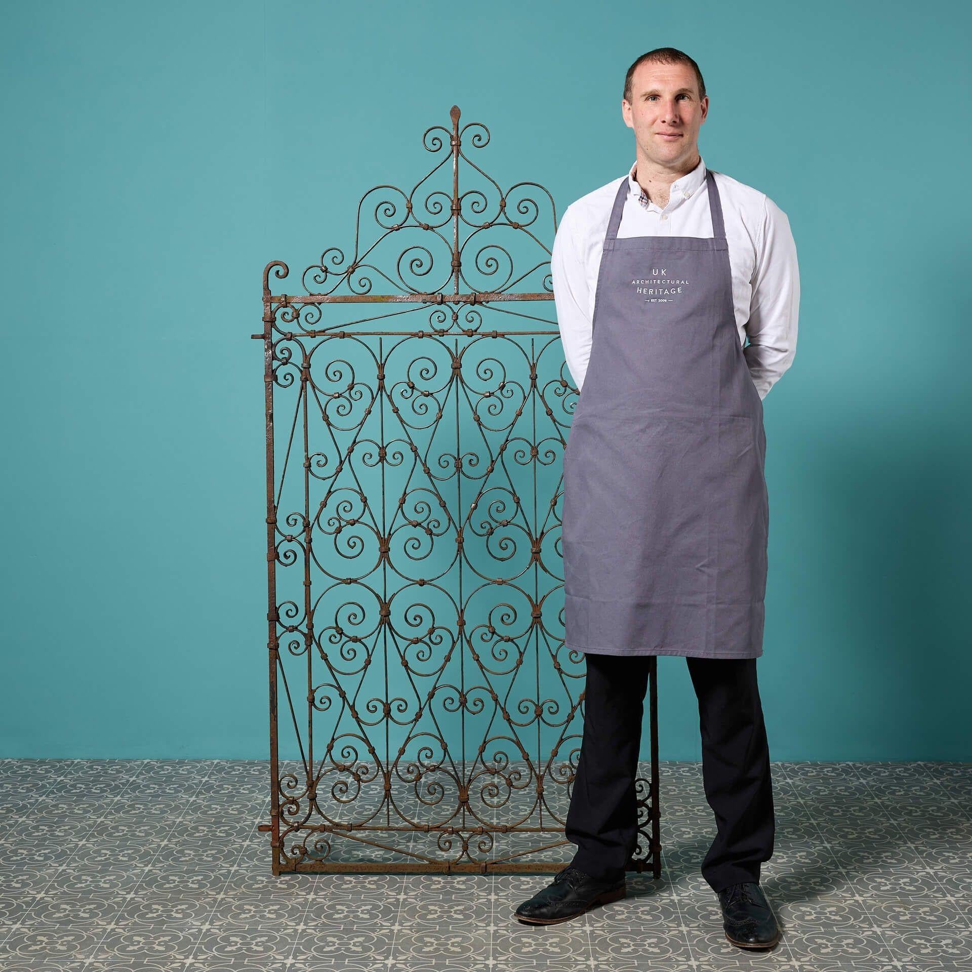A tall regency style wrought iron garden side gate, traditionally made at the hand of a skilled 19th century blacksmith, circa 1890. This antique gate will look beautiful in gardens of any age thanks to its abundance of timeless scrollwork, bringing