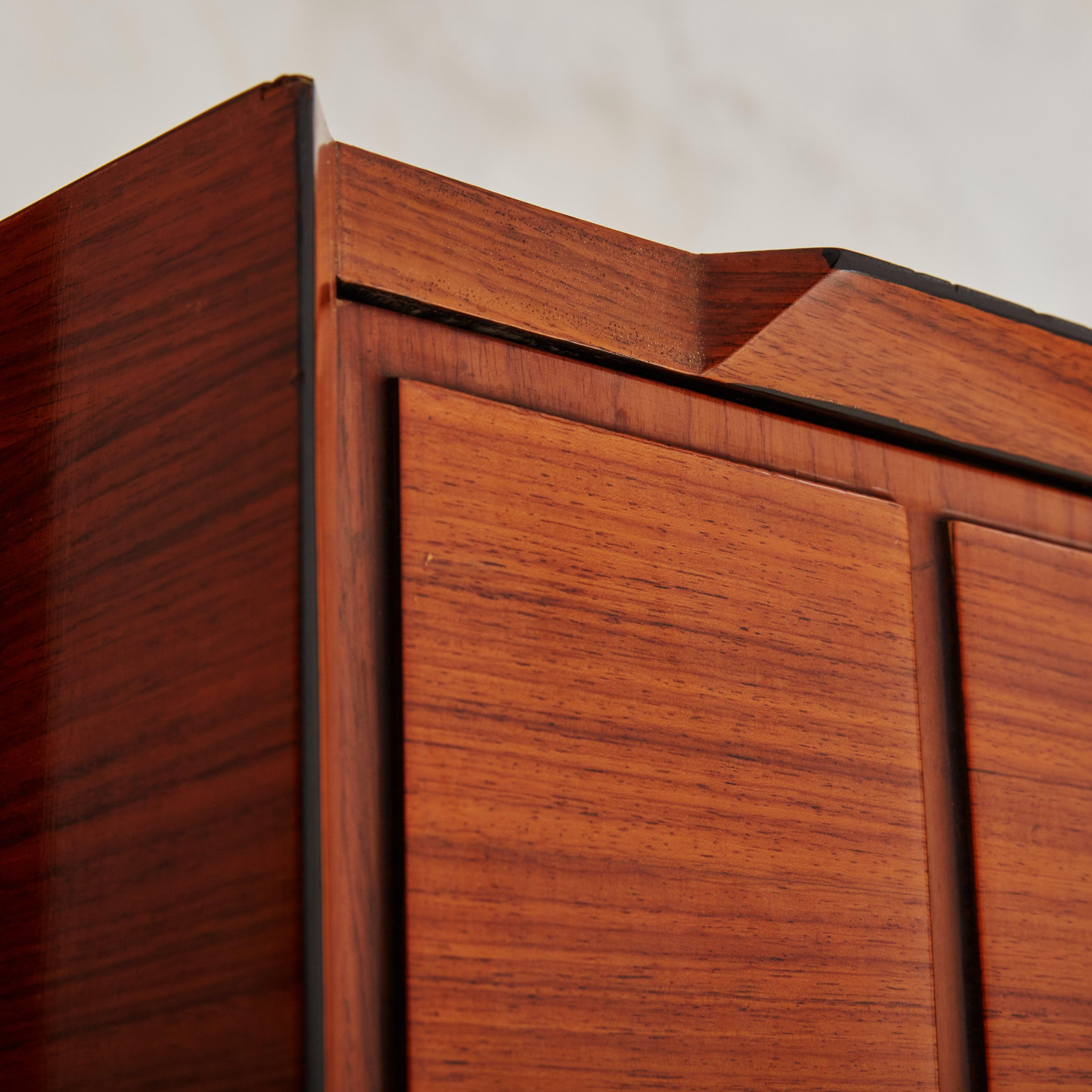 Mueble alto de la Edad Media de los años 50 diseñado en Francia por SAM (Société Auxiliaire du Meuble). Este impresionante mueble está fabricado en chapa de palisandro de tonos intensos y cuenta con dos estantes rectangulares inferiores y una sola