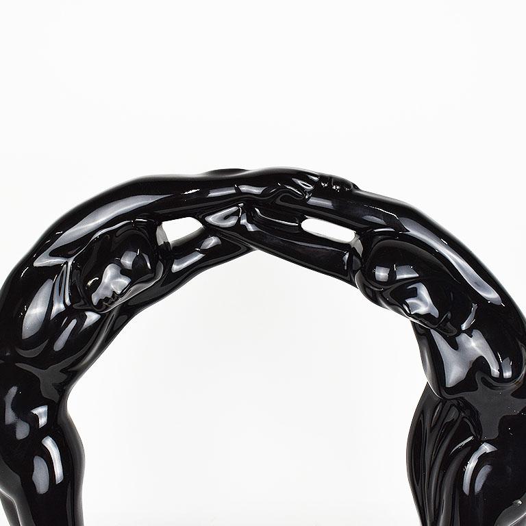 Large Haeger “Eternal Circle of Love” ceramic statue in black. This piece features a nude man and woman joining hands and feet in a circular form. A tall piece, it is glazed in a smooth, shiny black. Signed at bottom.

Dimensions:
14