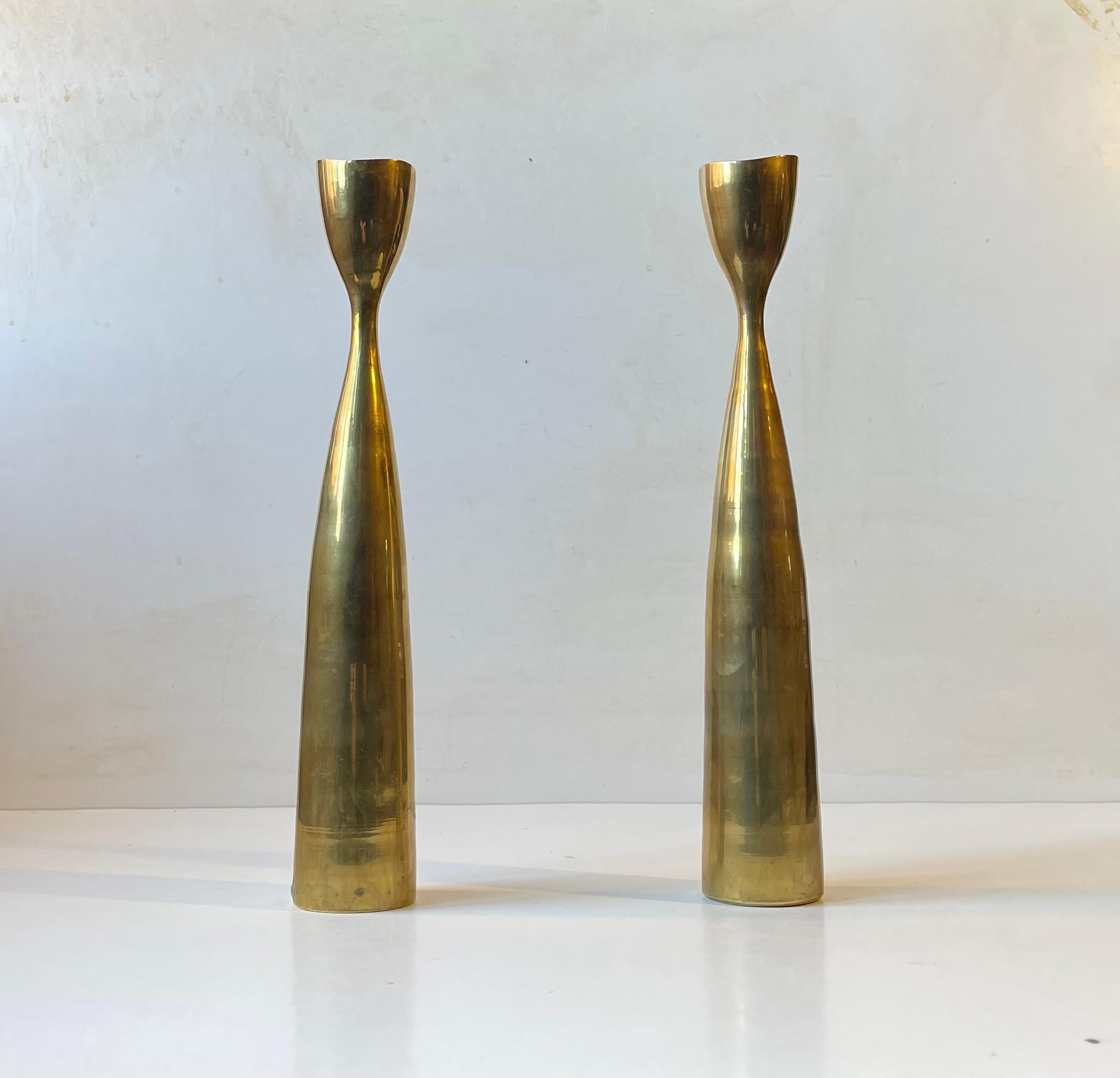 A pair of tall organically shaped tulip candlesticks in brass. Designed and manufactured in Scandinavia during the 1960s ina style reminiscent of Pierre Forssell and Jens Harald Quistgaard. The candlesticks are to be fitted with regular sixed