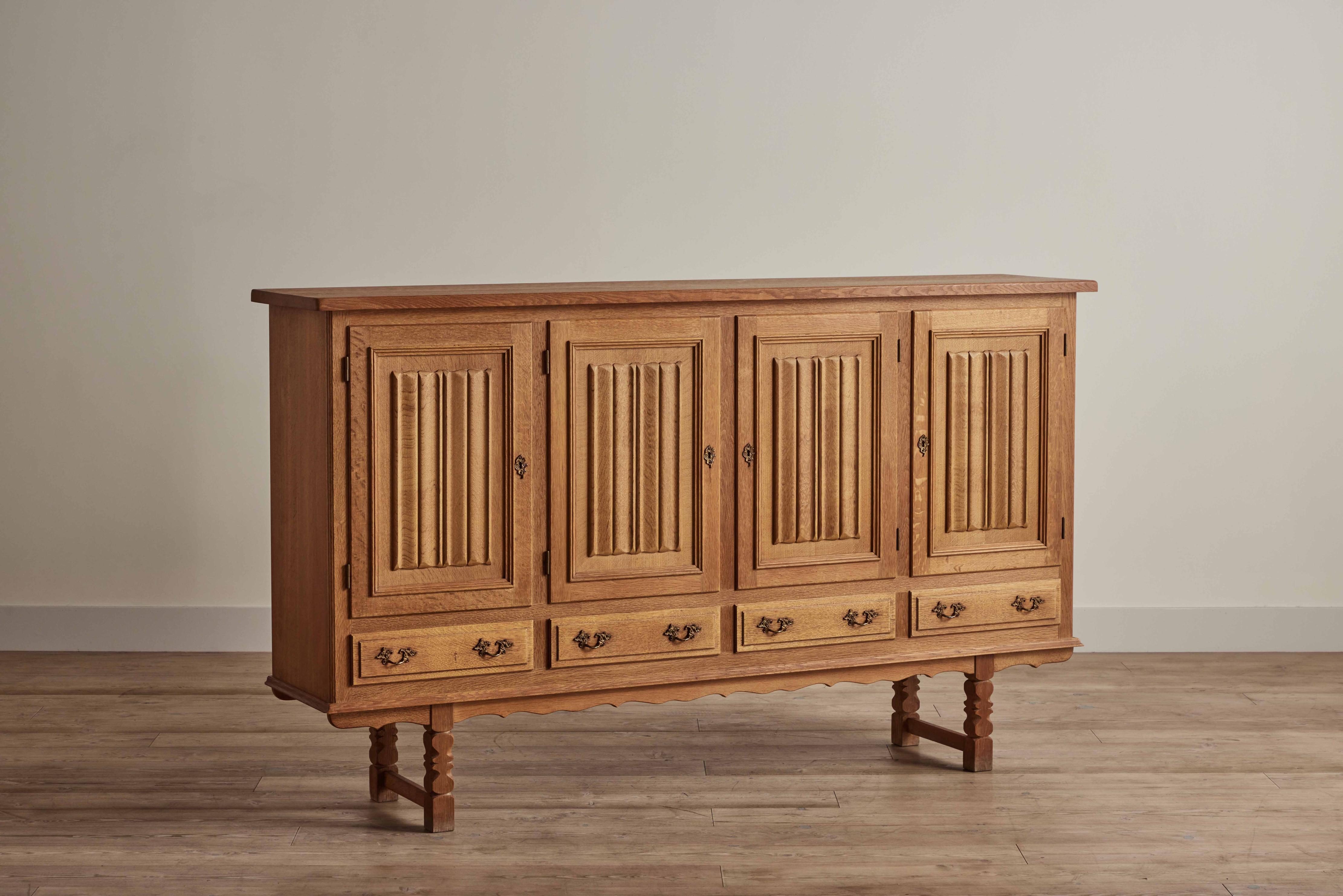 Tall sideboard attributed to Henning Kjaernulf from Denmark circa 1960. Made of solid hand-carved oak wood, this sideboard has four interior compartments and four drawers. Comes with a key. Wear on wood is consistent with age and use. 
