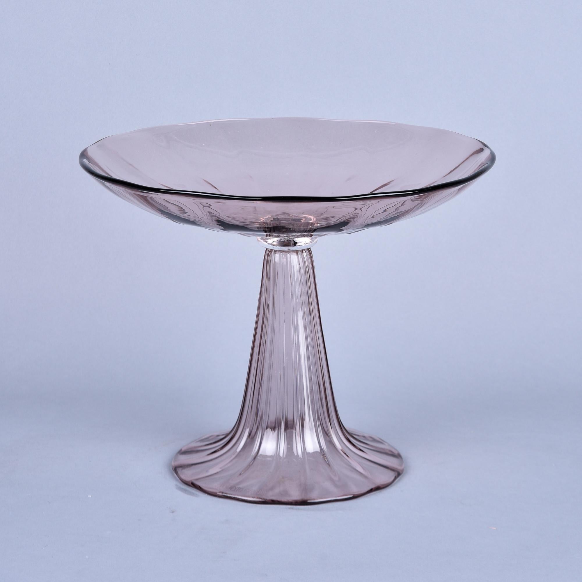 Found in Italy, this circa 2010 Murano glass tazza is marked Roberto Cavalli on the base. This pale amethyst tazza is over 12” high and 15” diameter with subtle ribbing to the surface. No chips, cracks, flaws or repairs found. 

Tazza is in