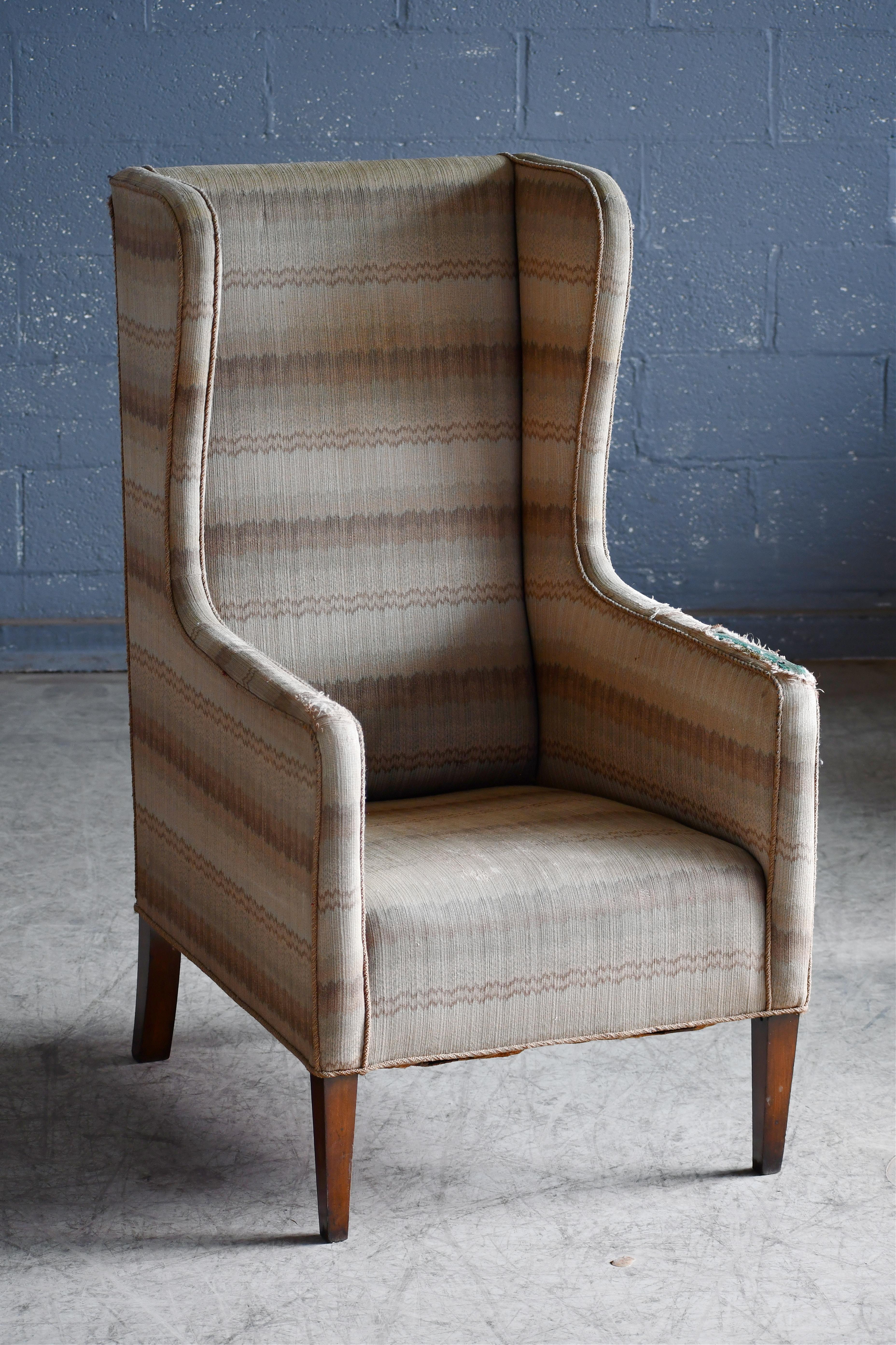 Sehr cooler Hochlehner-Sessel mit geknöpfter Rückenlehne, hergestellt in Dänemark um 1950. Schöne harmonische Proportionen mit einer schlanken und hohen Silhouette und etwas kantigen Linien im Stil von Frits Henningsen. Äußerst stilvoll und