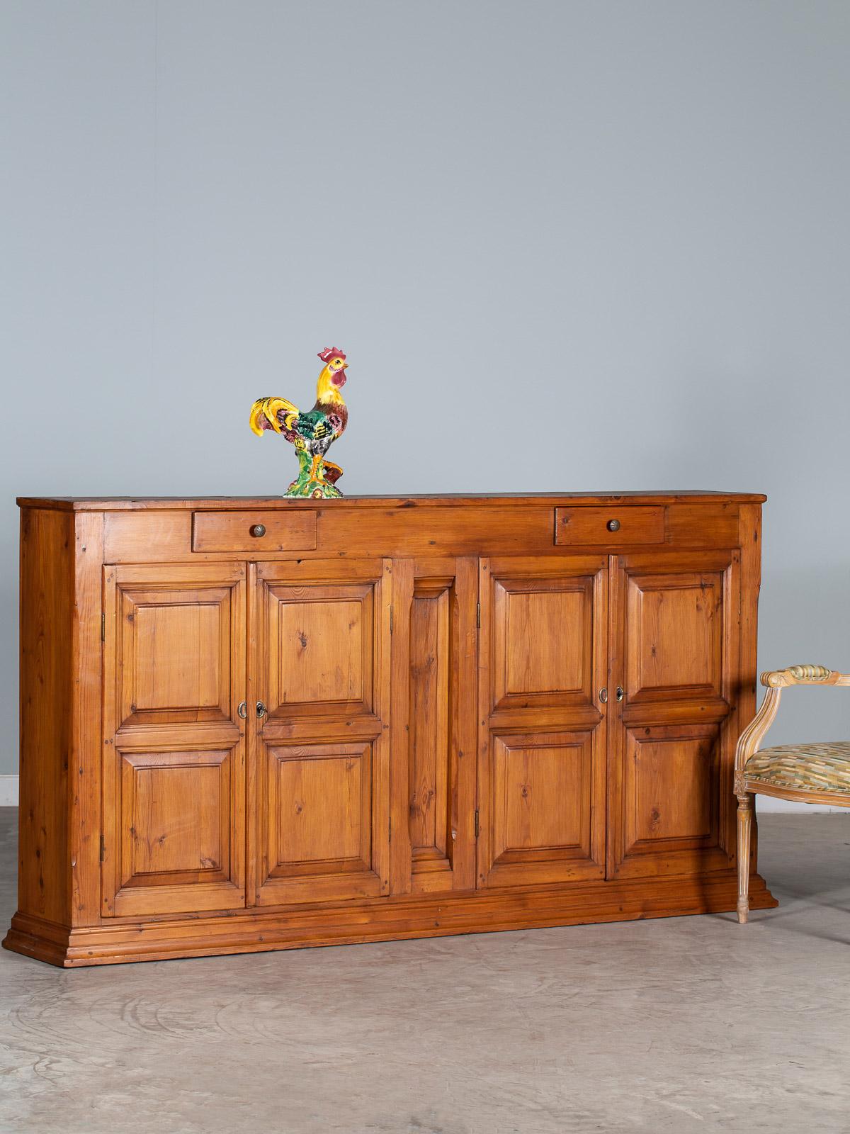 This tall vintage French solid pine buffet credenza cabinet circa 1930 features four cabinet doors made of deeply recessed panels and molding and two drawers just below the top and centered over the cabinet doors. Heavy and substantial this piece
