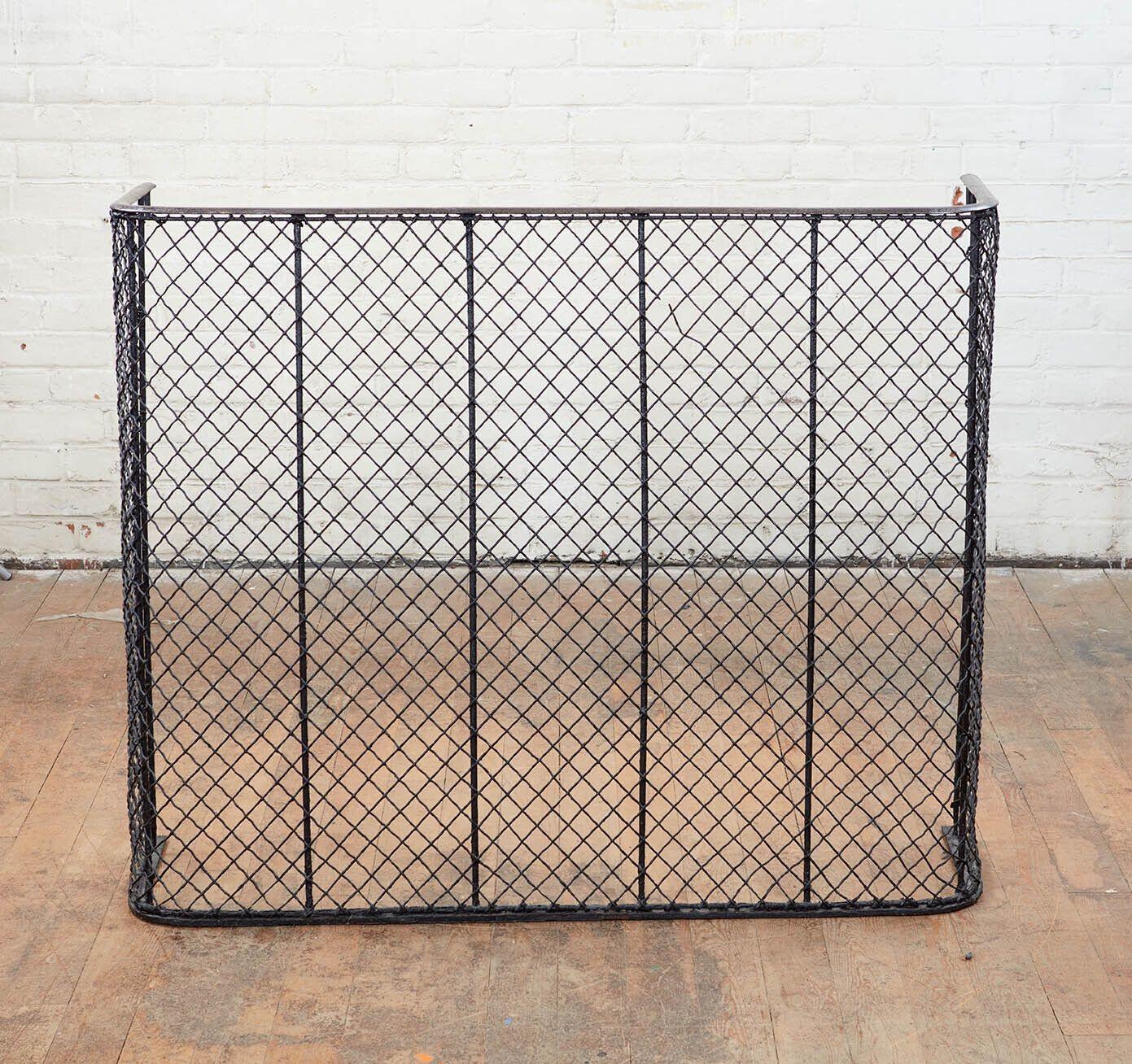 A large fireplace guard with heavy iron cross hatched wire netting and iron base and rod supports topped by a steel rail. Known as a nursery guard as it is not meant as a spark guard, but is designed to keep children and dogs away from the fire. A