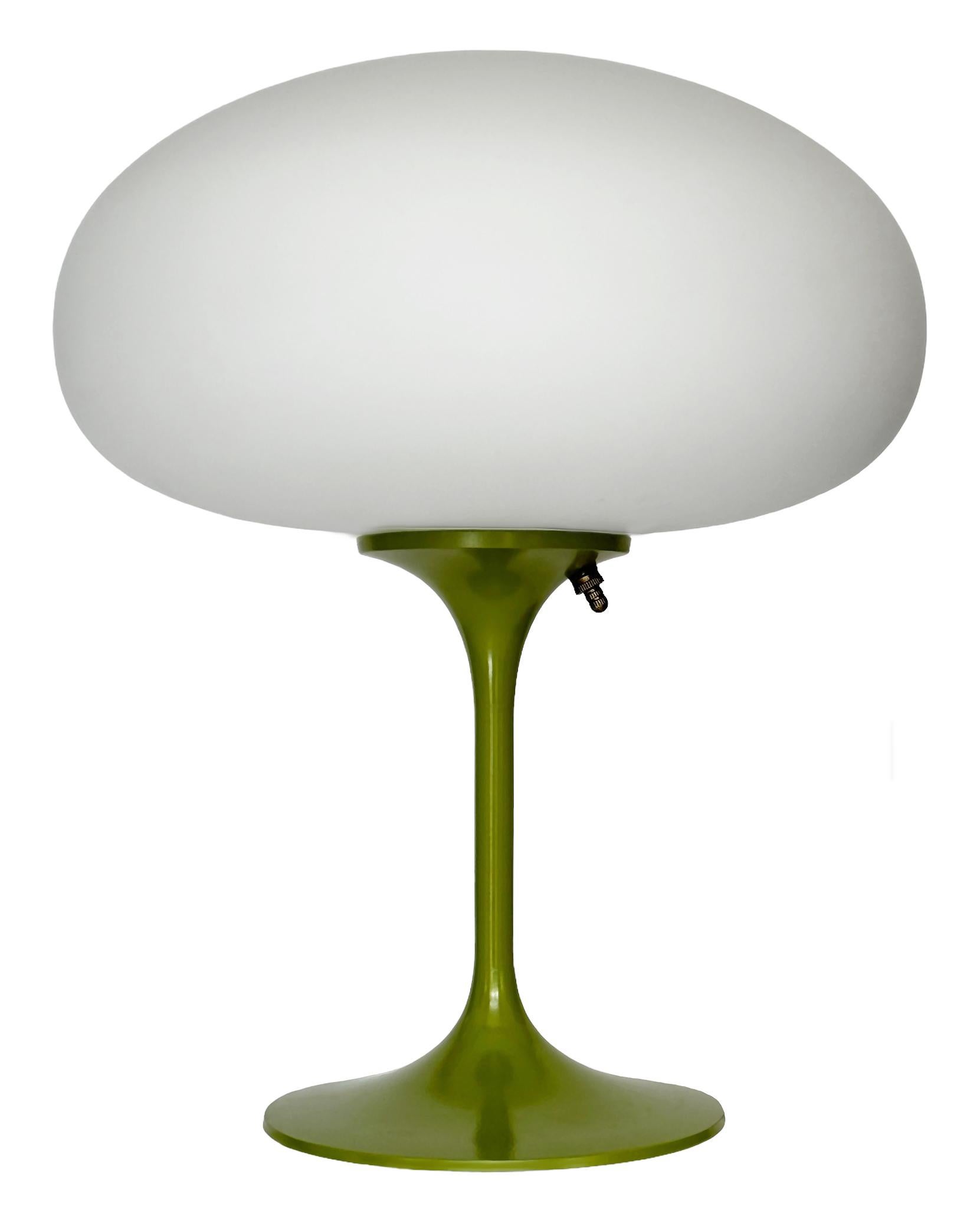 THIS ITEM IS ELIGIBLE FOR FREE SHIPPING!

A sleek stemlite table lamp made by Design Line. It features a cast aluminum main base in a sculptural tulip form. The lamp base is finished in a retro avocado green color. The frosted glass lamp shade is