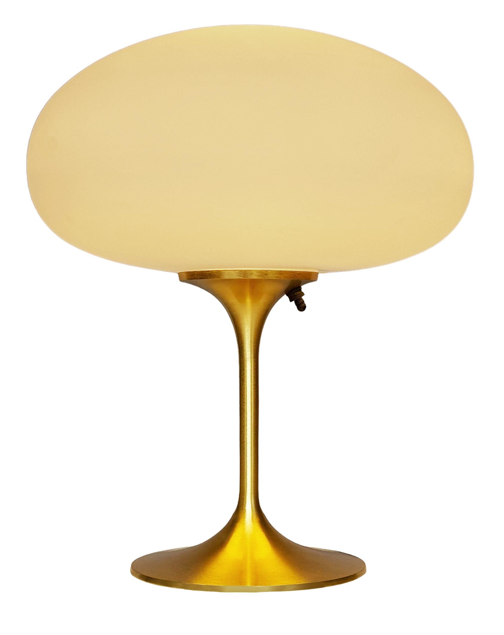 THIS ITEM IS ELIGIBLE FOR FREE SHIPPING!

A sleek stemlite table lamp made by Design Line. It features a cast aluminum main base in a sculptural tulip form. The lamp base is finished in a brushed brass / gold finish. The frosted glass lamp shade is