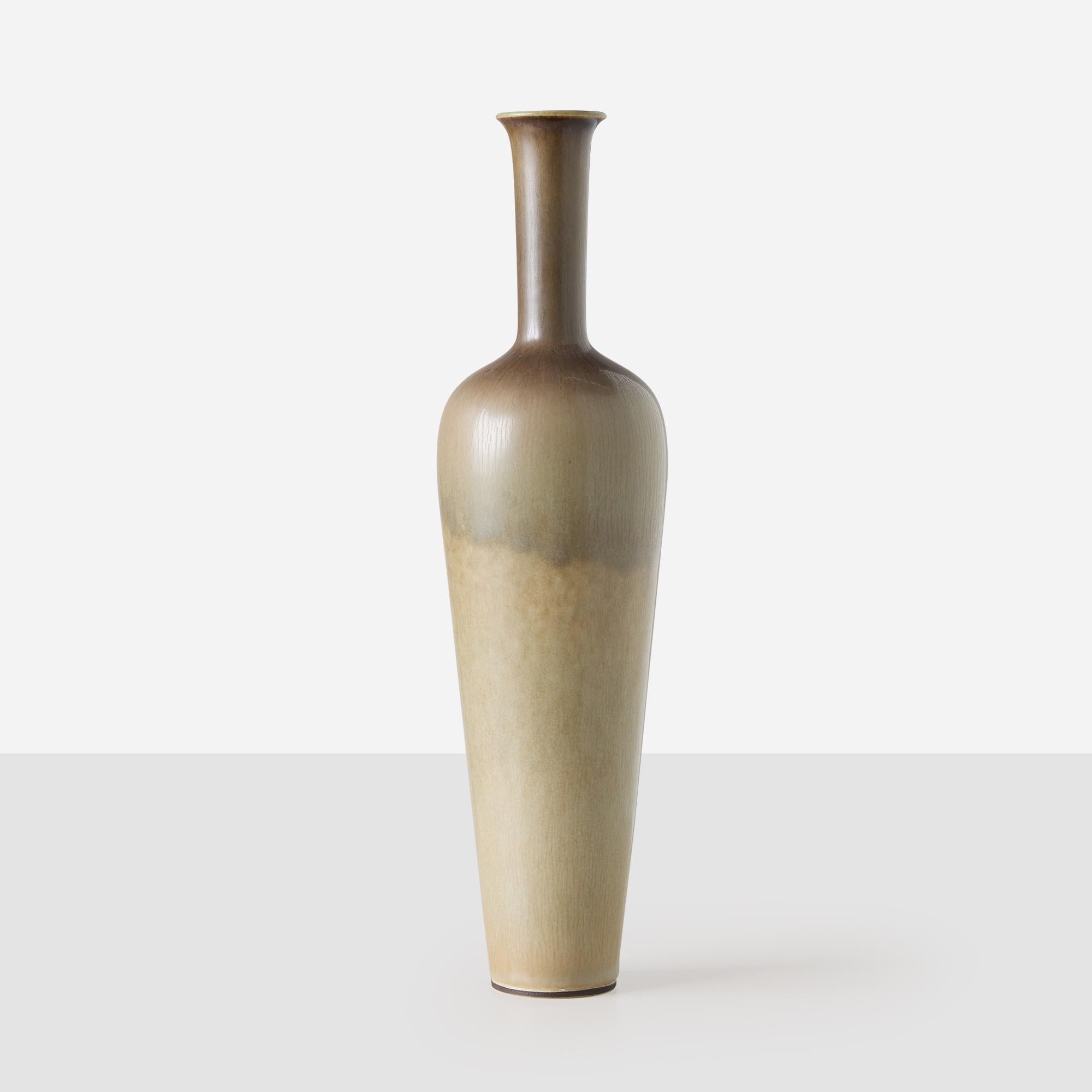 Questo vaso in gres di Berndt Friberg, lavorato a ruota, presenta un collo allungato e sottile e uno smalto liscio nelle tonalità della terra chiara. È un esempio della raffinata maestria artigianale e dell'eleganza delle forme di Friberg. Il lato