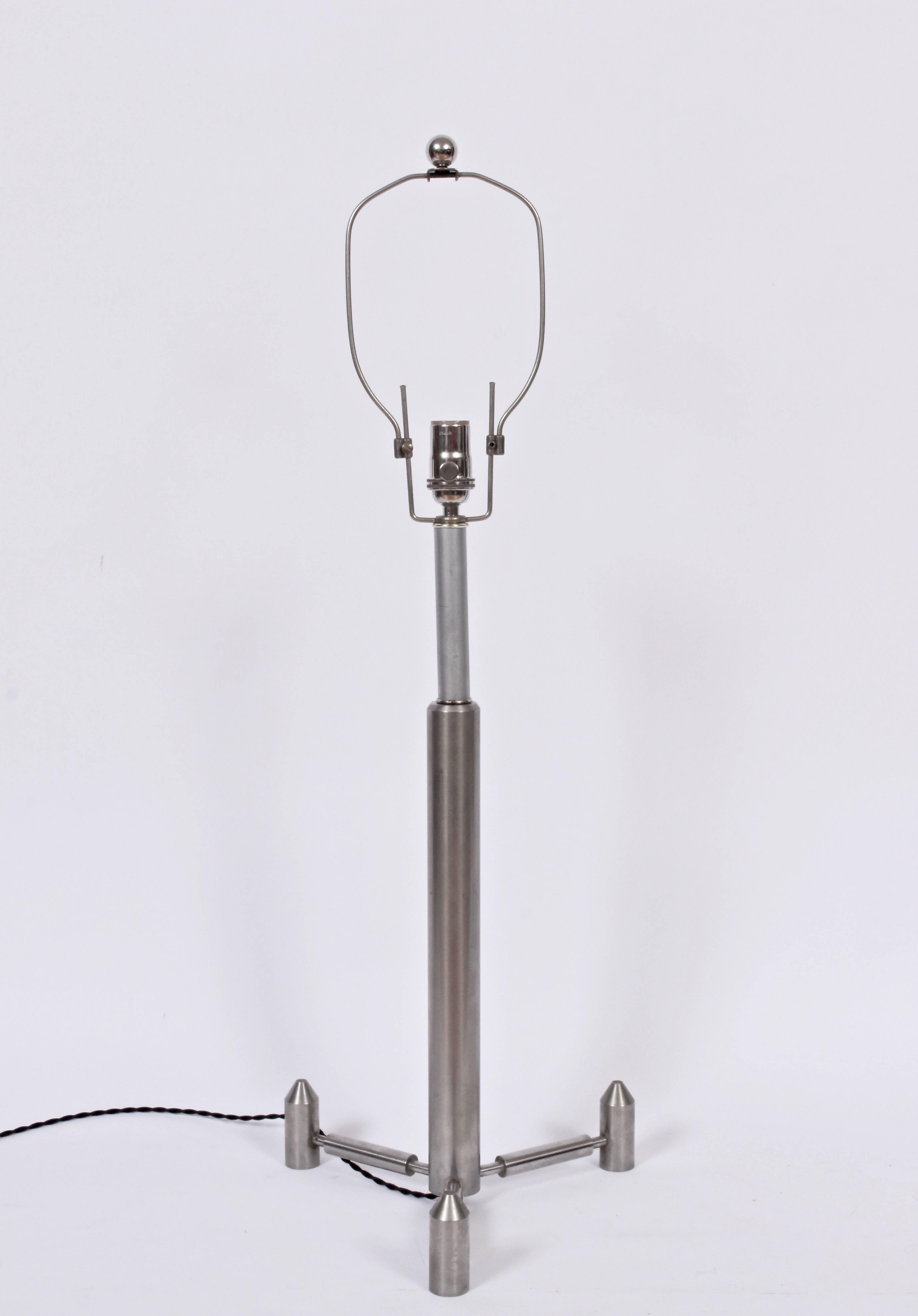 Sustancial Lámpara de Sobremesa Studio Aeronáutica de Acero Cepillado. Con un trípode artesanal en forma de cohete A sobre una base de trípode con patas. Arpa original ajustable; se desplaza hacia arriba y hacia abajo 5 cm. Arpa mostrada en posición