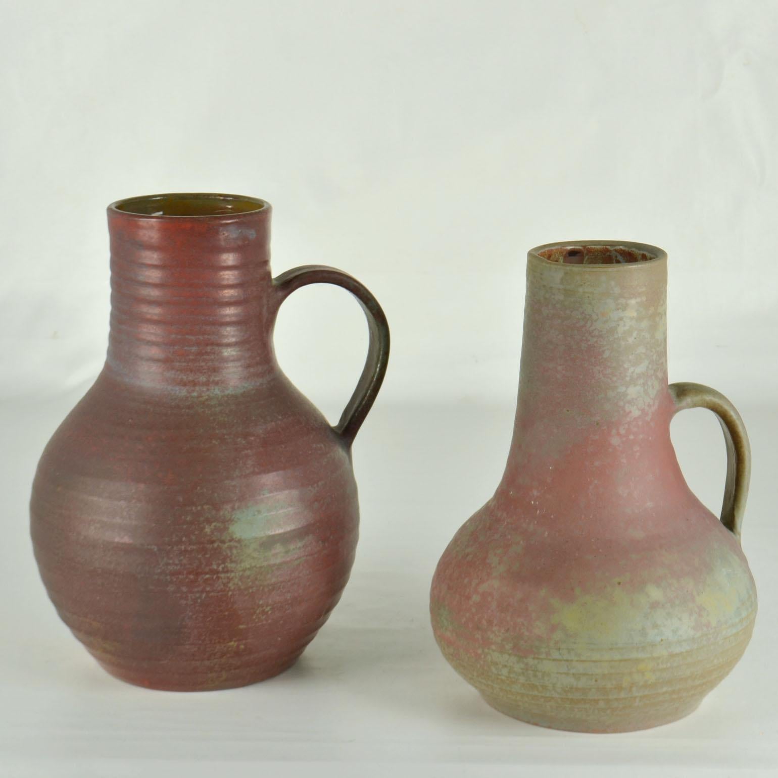 Two hand turned studio pottery tall vases with ears with in earth tone glazes form deep dark red to grey-green. They are created on the turning wheel by highly technical skilled Dutch ceramist in the 1960's at studio DOK. The semi matte glaze and
