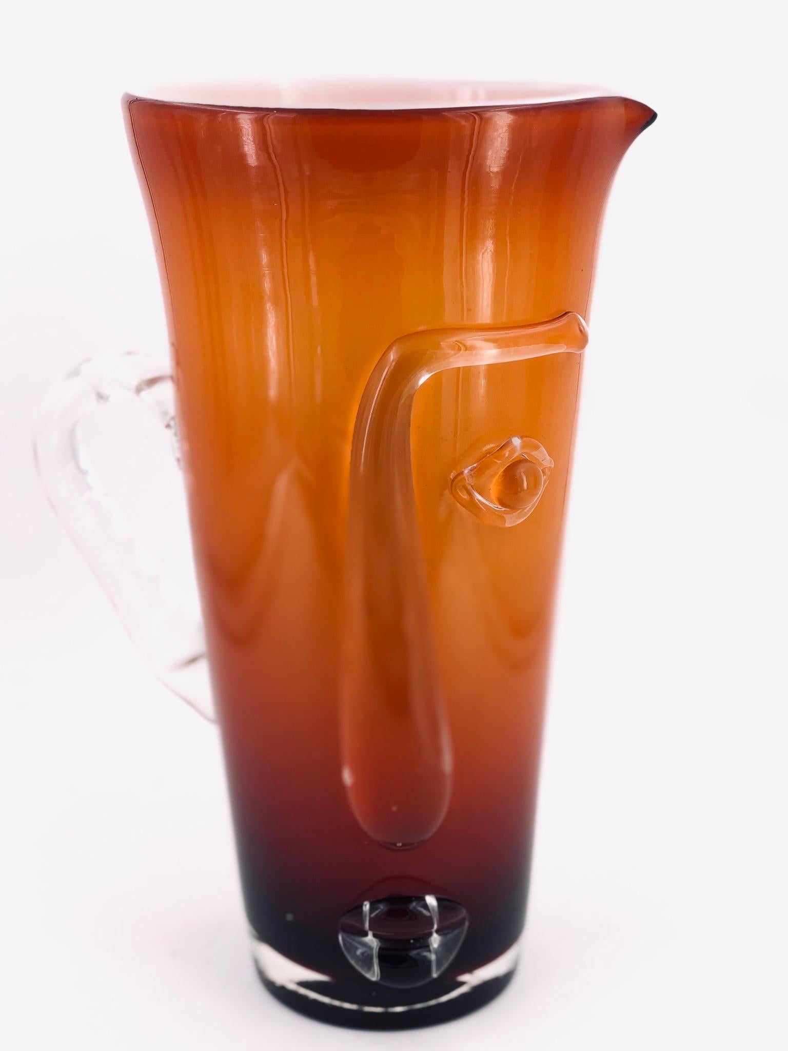 A beautiful and rare tall glass, a pitcher in a Picasso style cubist face the handle it's in a clear glass shaped like an ear, circa 1980s. Unsigned in great condition no chips or cracks. With the pontile mark on the bottom.