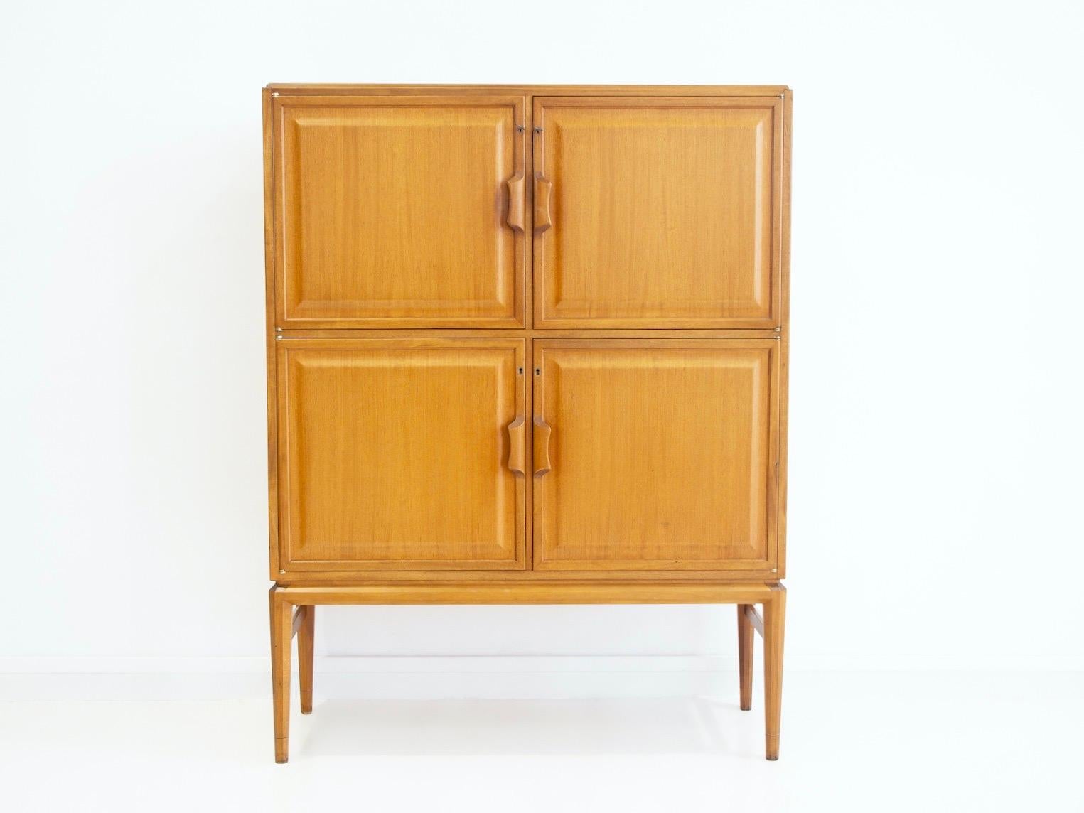 Armoire The Modern Scandinavian en acajou avec quatre portes frontales, derrière lesquelles se trouvent des étagères et des plateaux coulissants, vers 1960. Deux plateaux doublés de tissu bleu. Clés incluses. Labellisé à l'intérieur d'une porte par