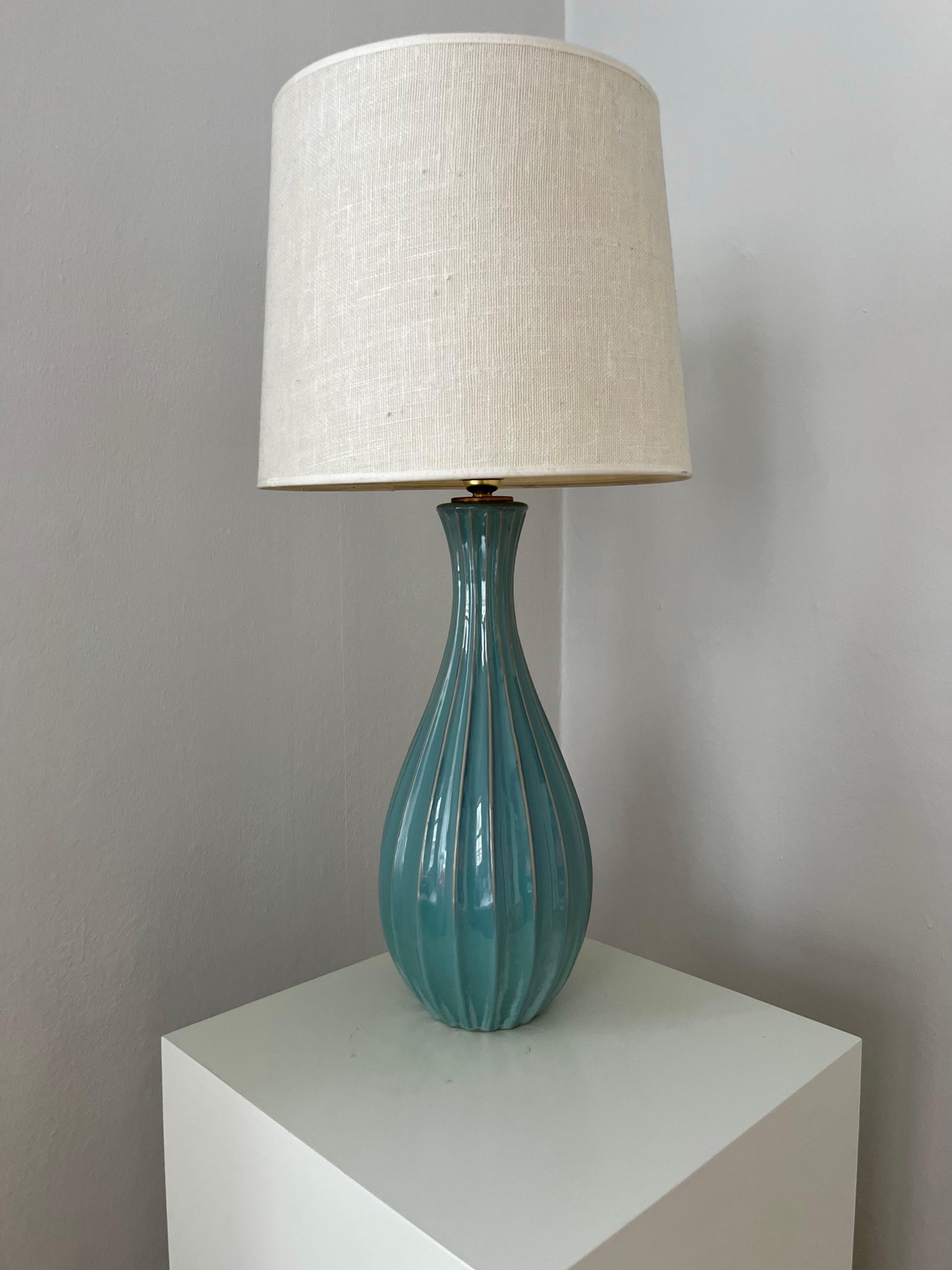 Tall Swedish Mid-Century fluted ceramic table lamp. This amazing, tall table lamp is made in fluted ceramic with a shiny blue/turquoise glaze and has a golden socket. 
It is 49,5 cm tall (19.49 in) with the socket, and it has a diameter of 18 cm