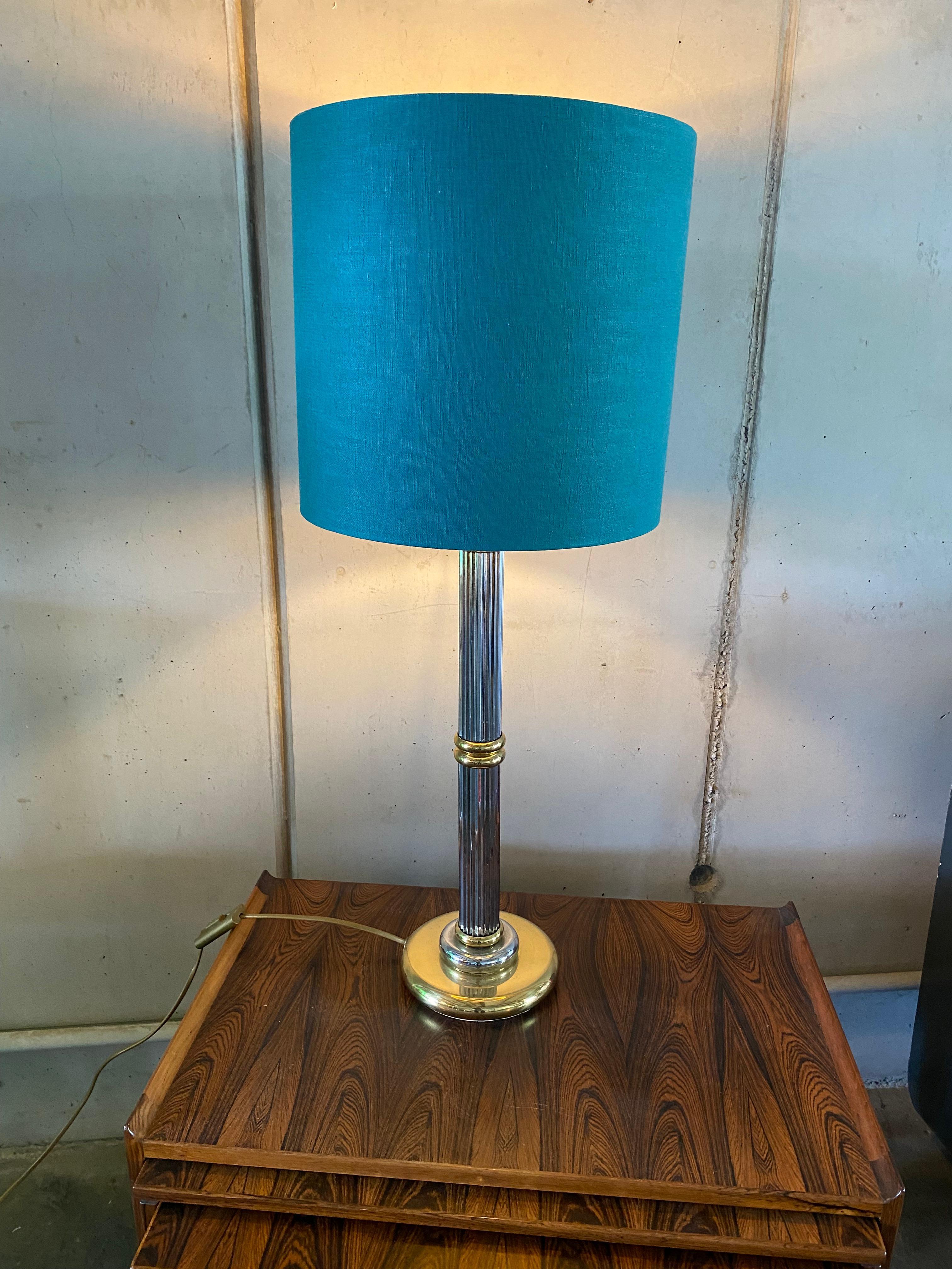 This tall metal table lamp is designed in a bi-color style. This means that gold and silver are combined with each other. The lamp base is fluted (the fluting is the vertical groove of an object, usually a column, a pillar or a pilaster with concave