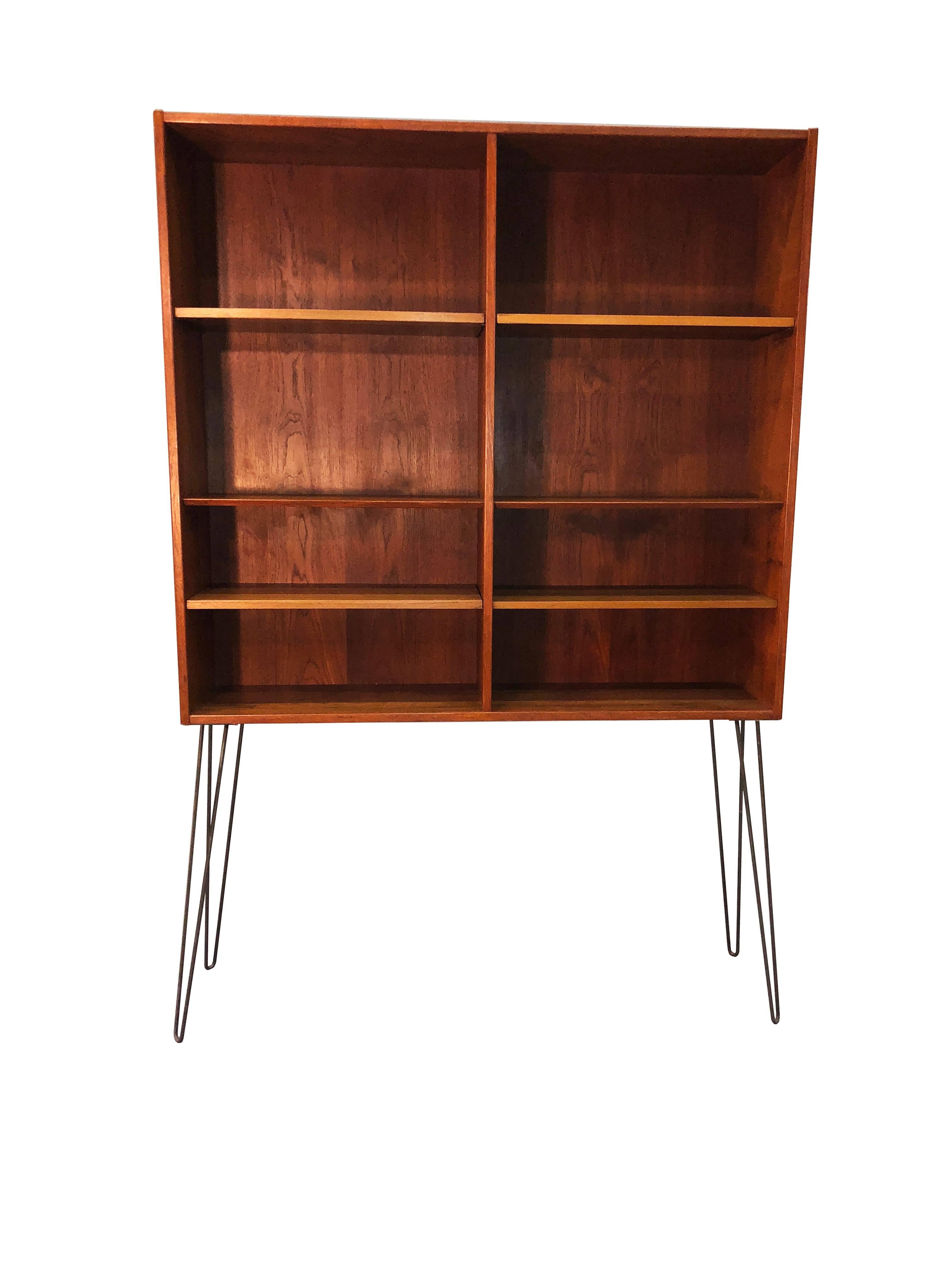 Vintage 1960s tall teak wood bookcase with wrought iron legs. The top and bottom shelves adjust, the middle shelf does not adjust. No maker's mark.