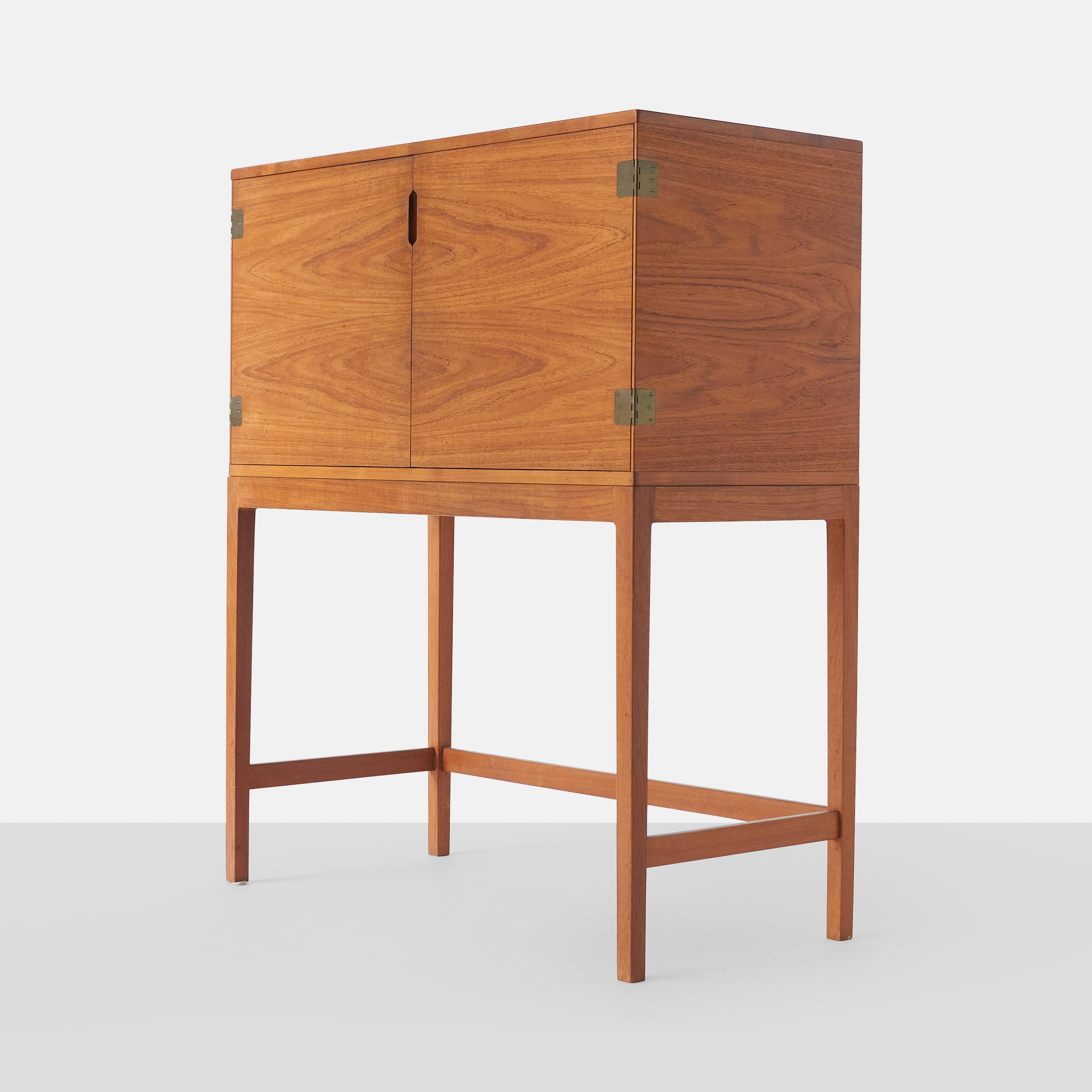 A Svend Langkilde teak cabinet with two doors enclosing adjustable shelves and four drawers. Doors with brass fittings.
