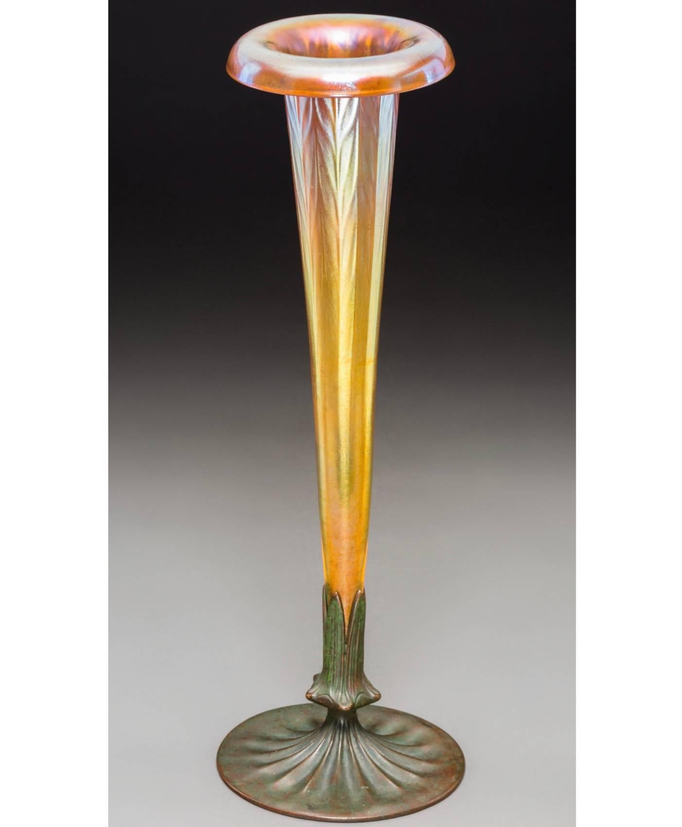 A Tall Iridescent Favrile Patterned and Decorated Tiffany Furnaces Gold Favrile Glass and Bronze Trumpet Vase. Art Nouveau, Art Deco transition, circa 1920-1928. 

Vase Engraved L.C.T 215. Base Stamped with logotype and LOUIS C. TIFFANY
