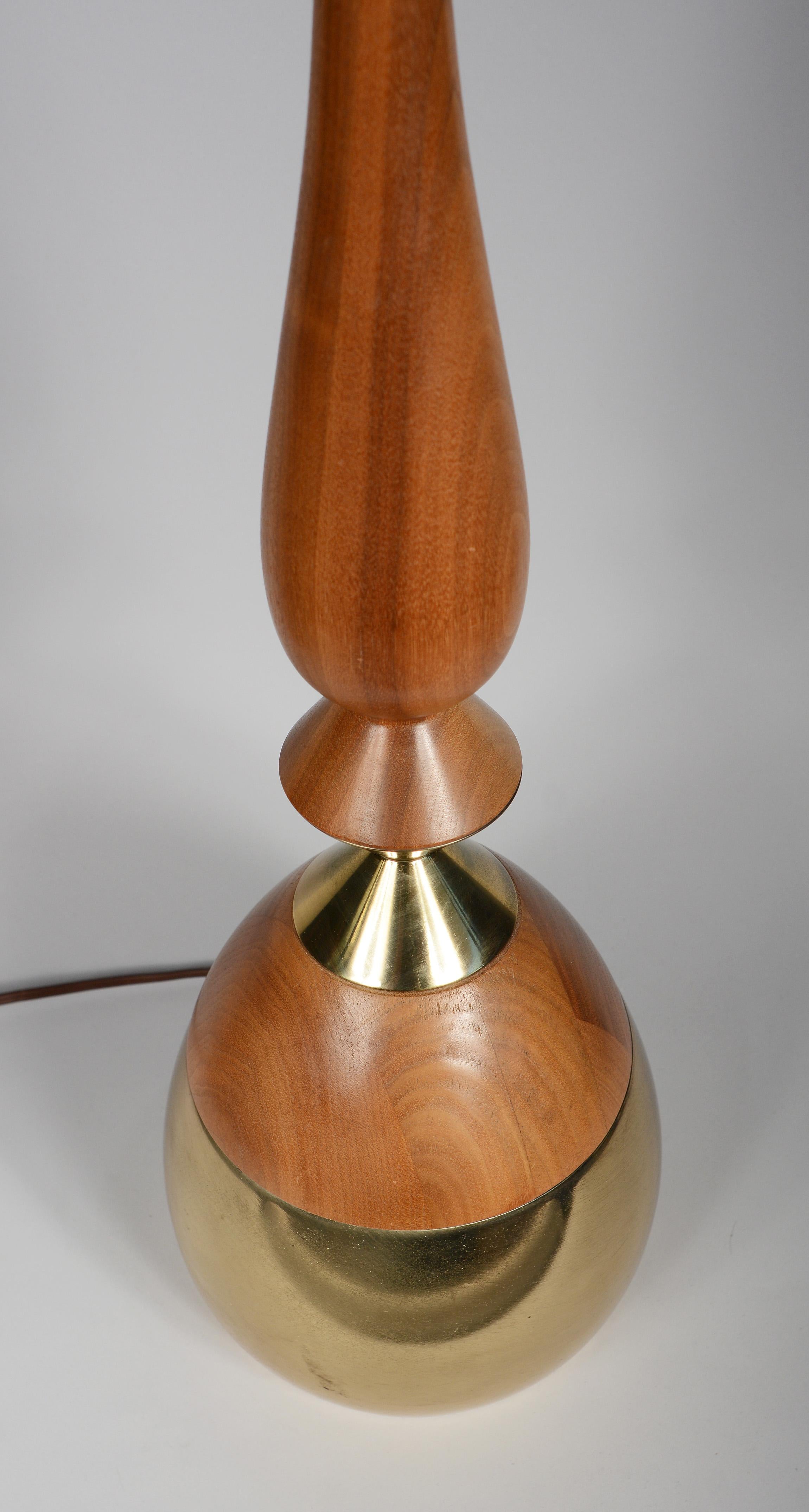 Tall walnut and brass table lamp designed by Tony Paul. This lamp has two turned walnut sections separated by an hourglass brass section atop a brass base. The lamp retains a portion of the Westwood label. The walnut is a little sun bleached with