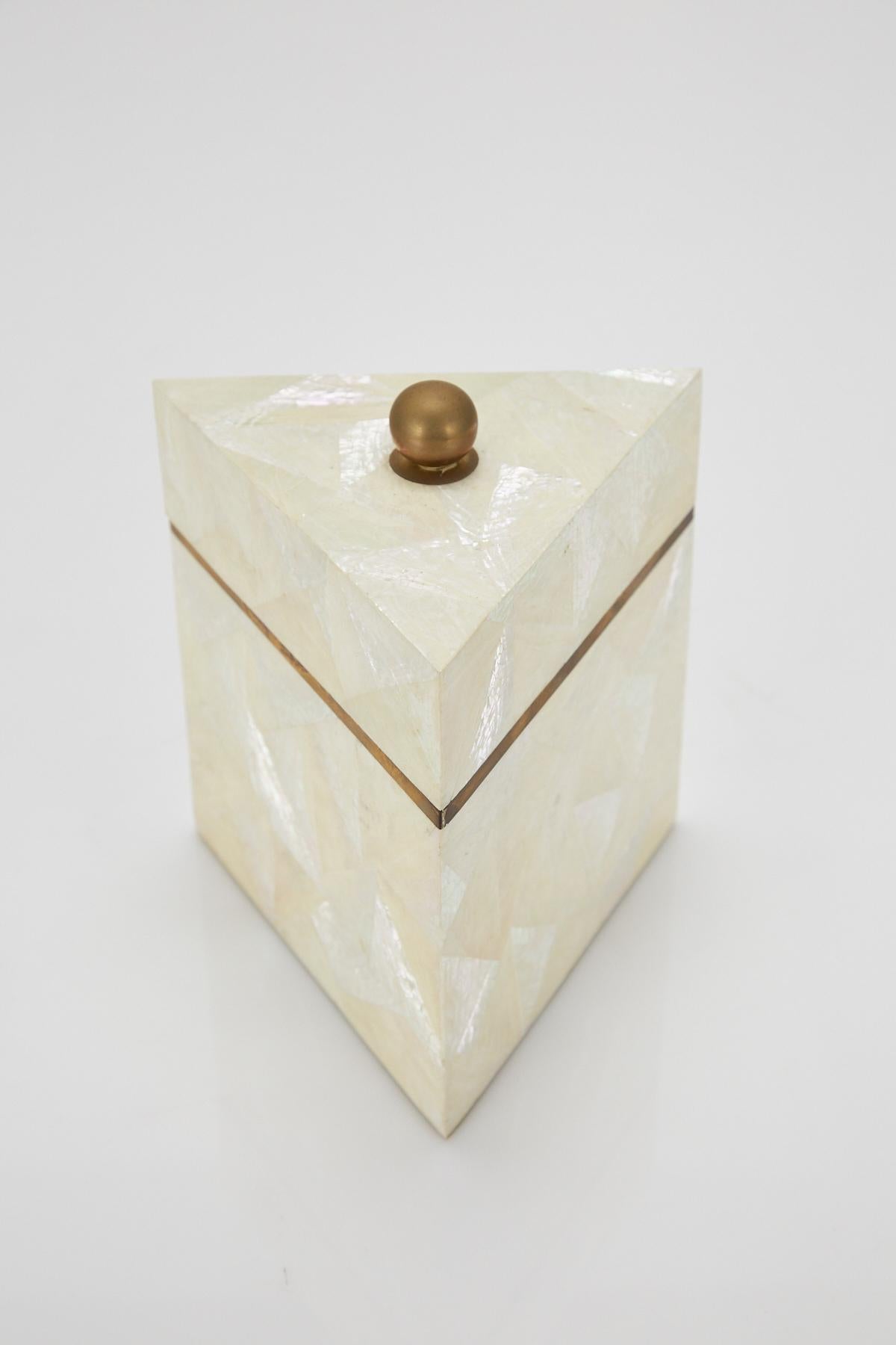 Tall triangular decorative box or tea caddy. Exterior completely covered in tessellated white stone and white chamber nautilus shell. Interior of box lined in wood. Brass edging and spherical handle.
Coordinates with item LU1484212589641.

All