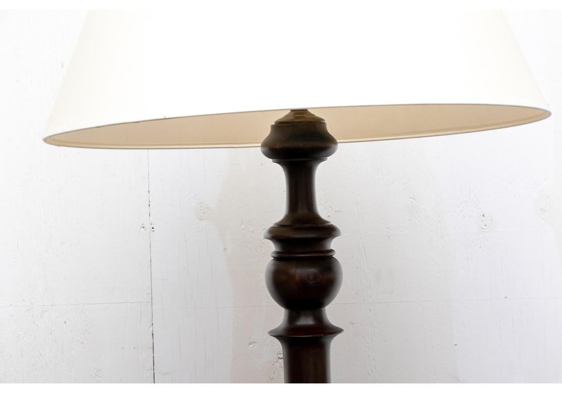 In a dark stain with turned top and bottom and slender tapering center support. Mounted on a turned dish form base. With white paper shade,

Dimensions: H. 73