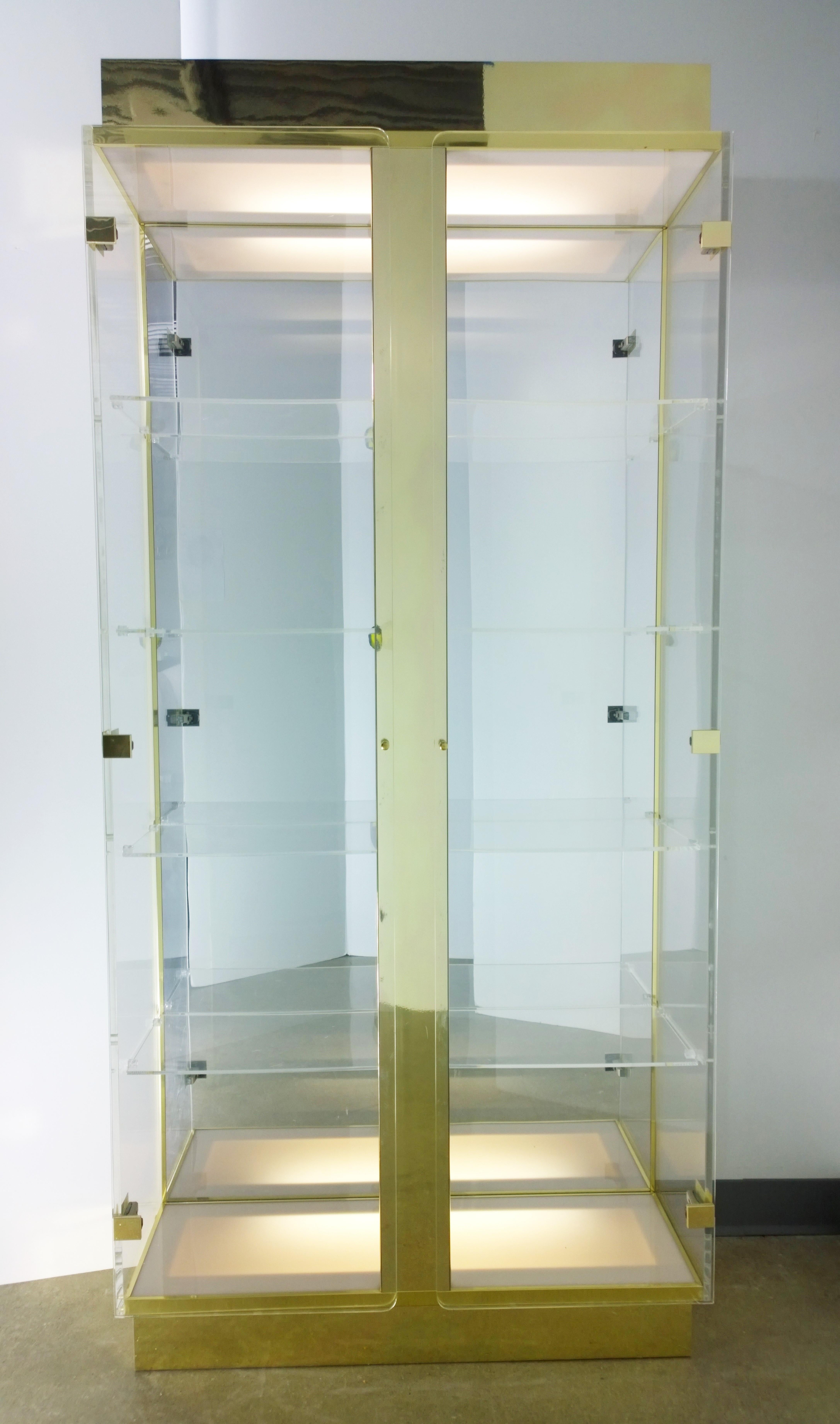 Offered is a Mid-Century Modern five Lucite shelves, Lucite supports, two Lucite doors, mirrored plastic, enameled gold plastic, brass over wood frame with upper and lower lighting. The sides and doors of this fabulous piece is made of Lucite. The