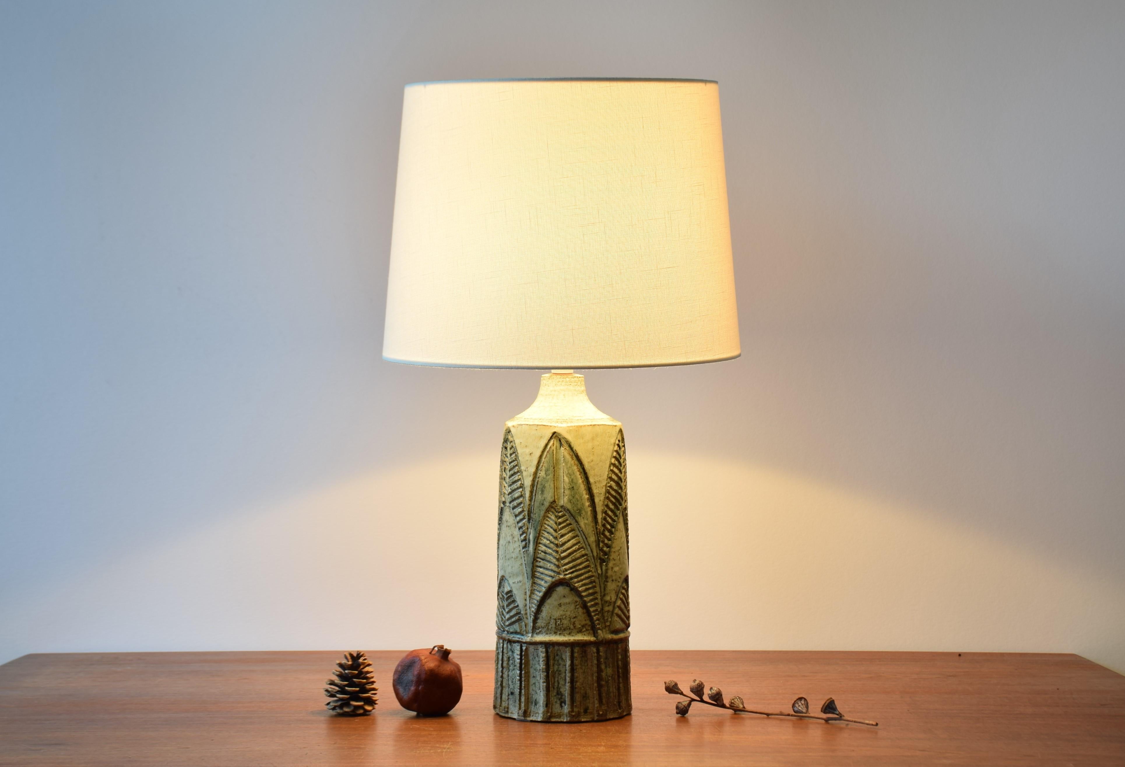 Tall and unique table lamp by Noomi Backhausen for Danish stoneware manufacturer Søholm.
Made ca 1960s.

The lamp shows a stylized leaf or tree motifs in relief and is covered with glaze in greenish and brown nature-like colors. The structured