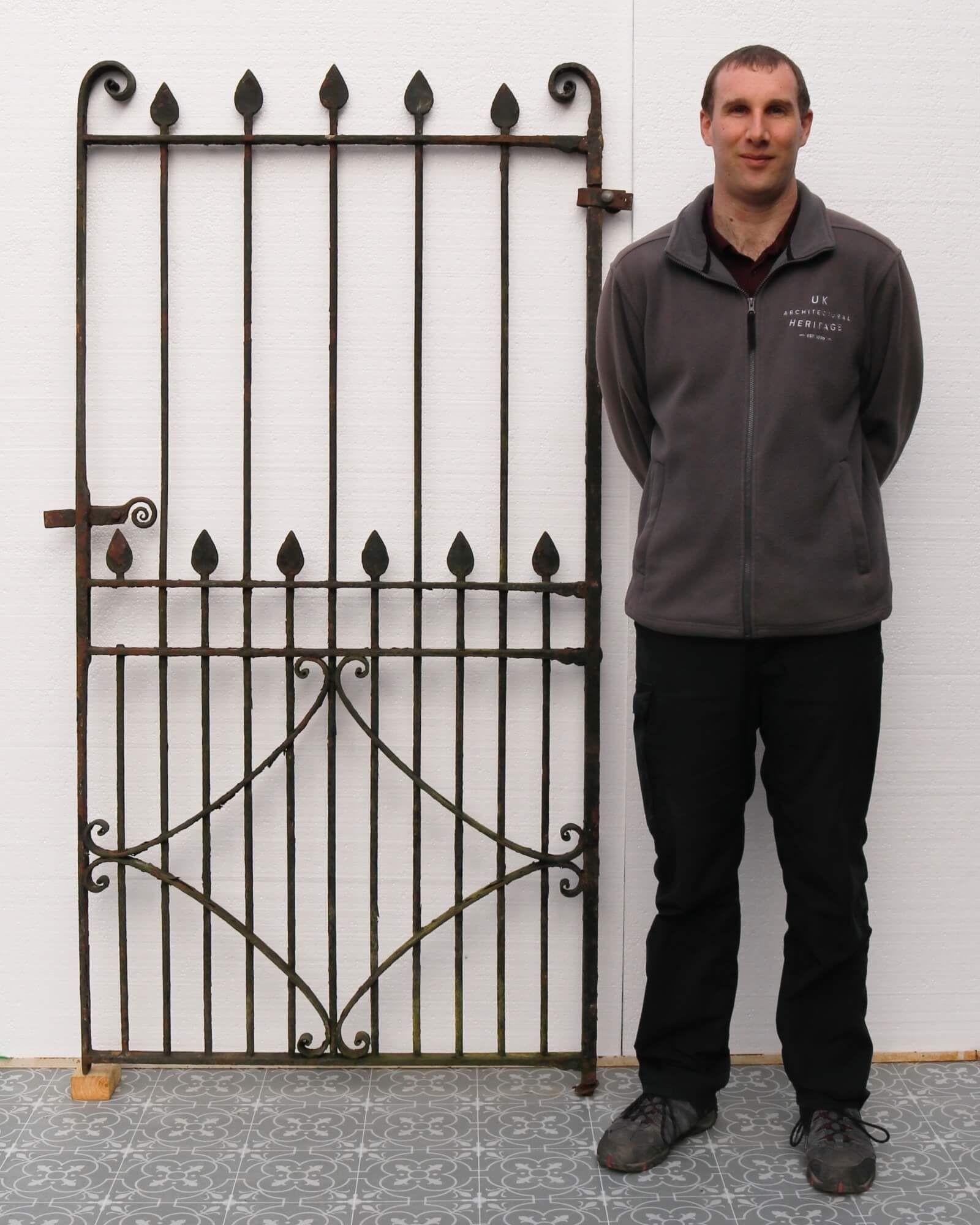 A handsome Victorian wrought iron side gate, perfectly proportioned for placement along the side of a house or for security in a narrow passageway. This tall antique gate has a simple yet stunning design, detailed with scrolls and curved arrowhead