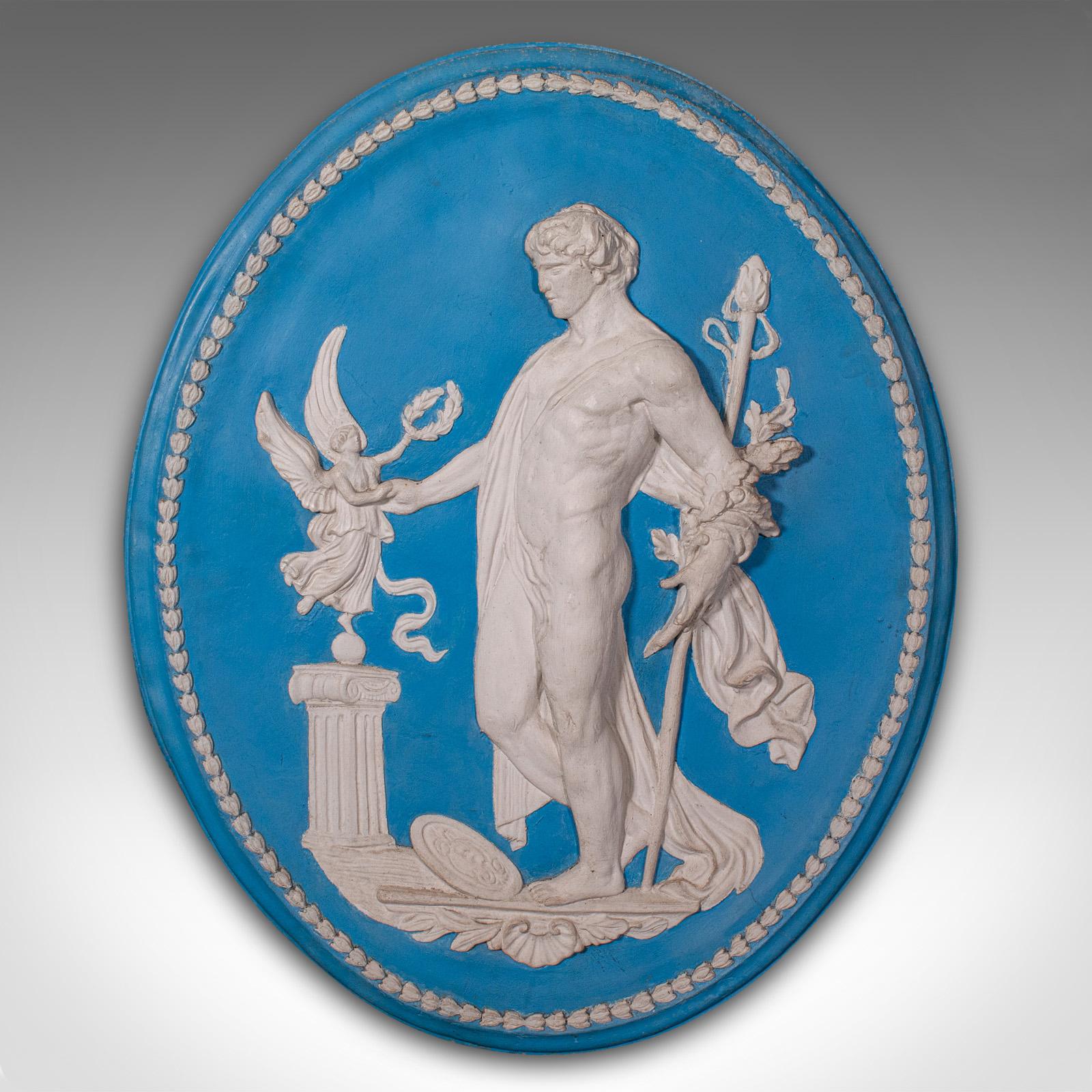 This is a tall vintage decorative relief plaque. An English, reconstituted stone neo-classical oval frieze in the manner of Jasperware, dating to the late 20th century, circa 1980.

Delightful classical appeal, the cameo form inspired by