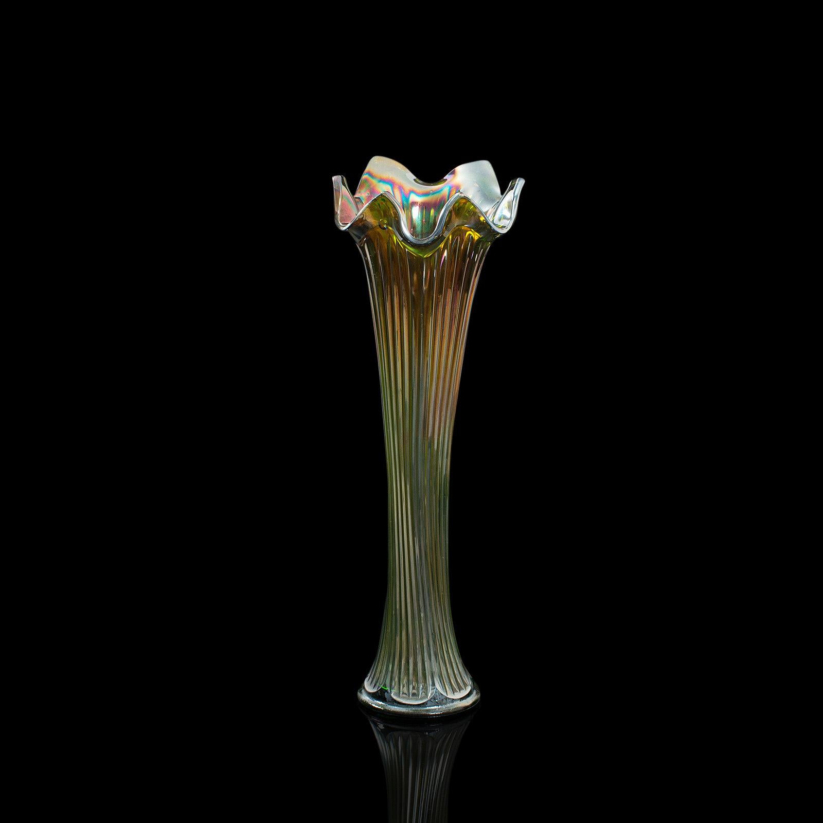 This is a tall vintage flower vase. An English, decorative glass carnival vase, dating to the early 20th century, circa 1930.

Desirably fluted, colorful flower vase
Displaying a desirable aged patina and in very good order
Green glass with