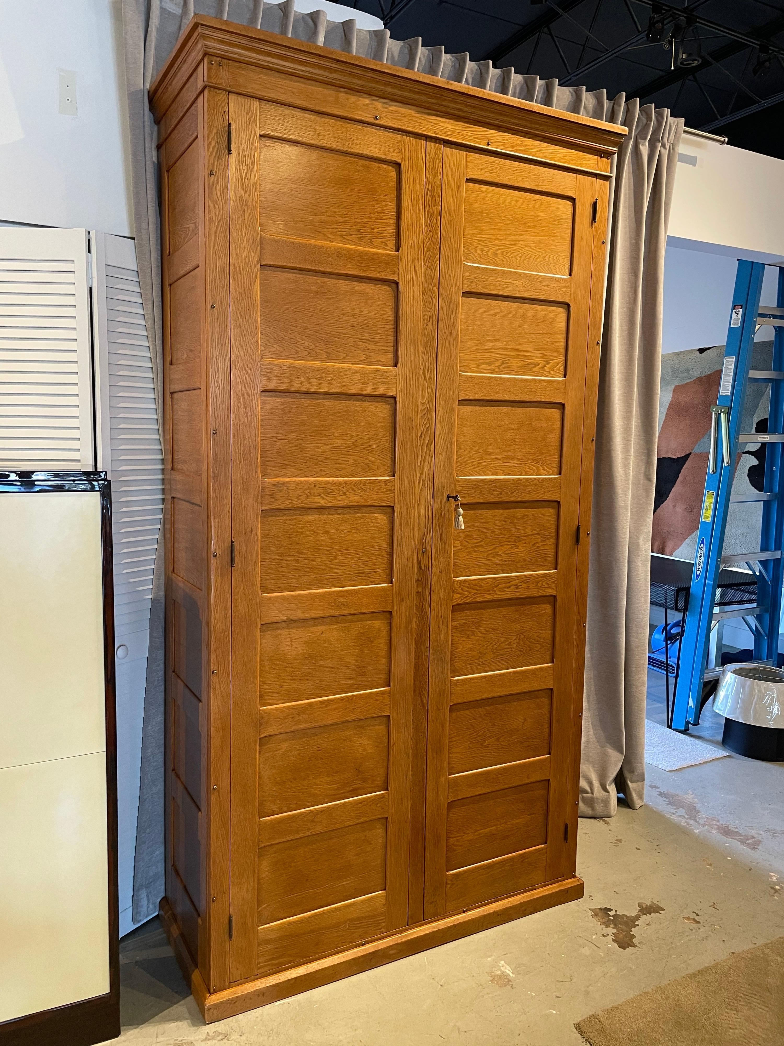 This is a wonderful natural oak cabinet with inset panels and two large doors which open to deep and wide shelving. Original key and lock. This has been lightly restored and the back panel to the wall was replaced. This is Jacques Adnet style with