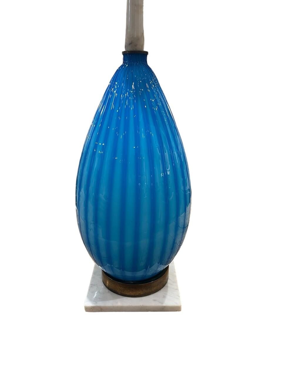 Elevate your space with timeless elegance courtesy of this exquisite Murano lamp. Standing at an impressive 41 inches, its hand-blown blue glass exudes sophistication. The marble base and neck add a touch of opulence, while the Italian craftsmanship