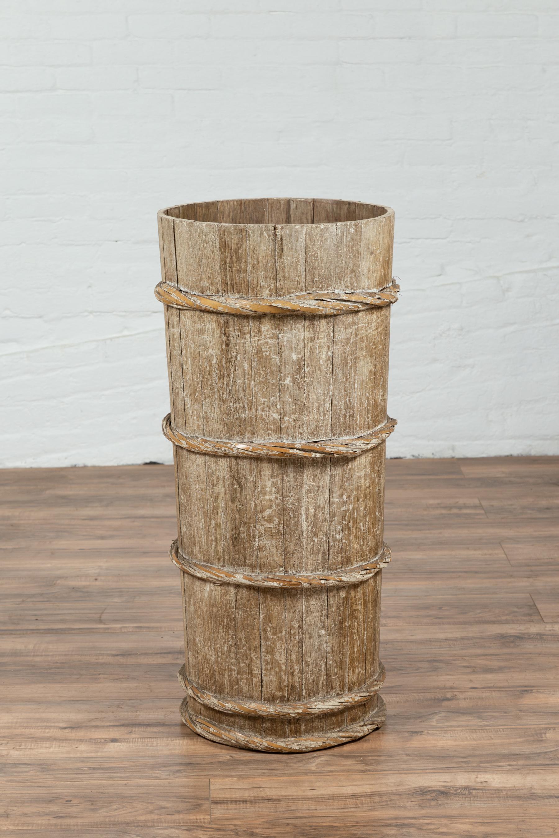 A tall vintage wooden barrel from Northern Thailand, with slatted body and rope-style motifs. We are immediately drawn to the rustic feel and great proportions of this Thai barrel. Presenting a slatted tapering body accented with horizontal twisted