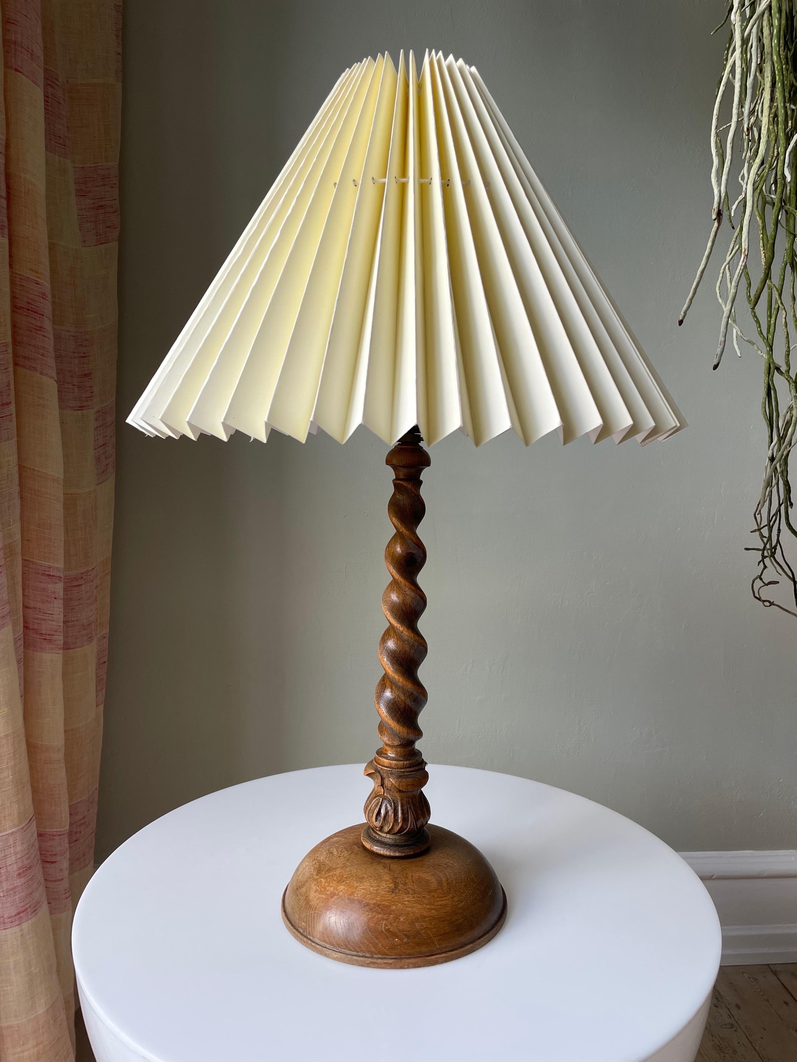 Large handcarved midcentury wooden table lamp. Clear lacquered swirling slender neck with intricate carved decor at the base and rounded foot. Original black fitting with switch and brass shade holder. Shade not included. Beautiful vintage