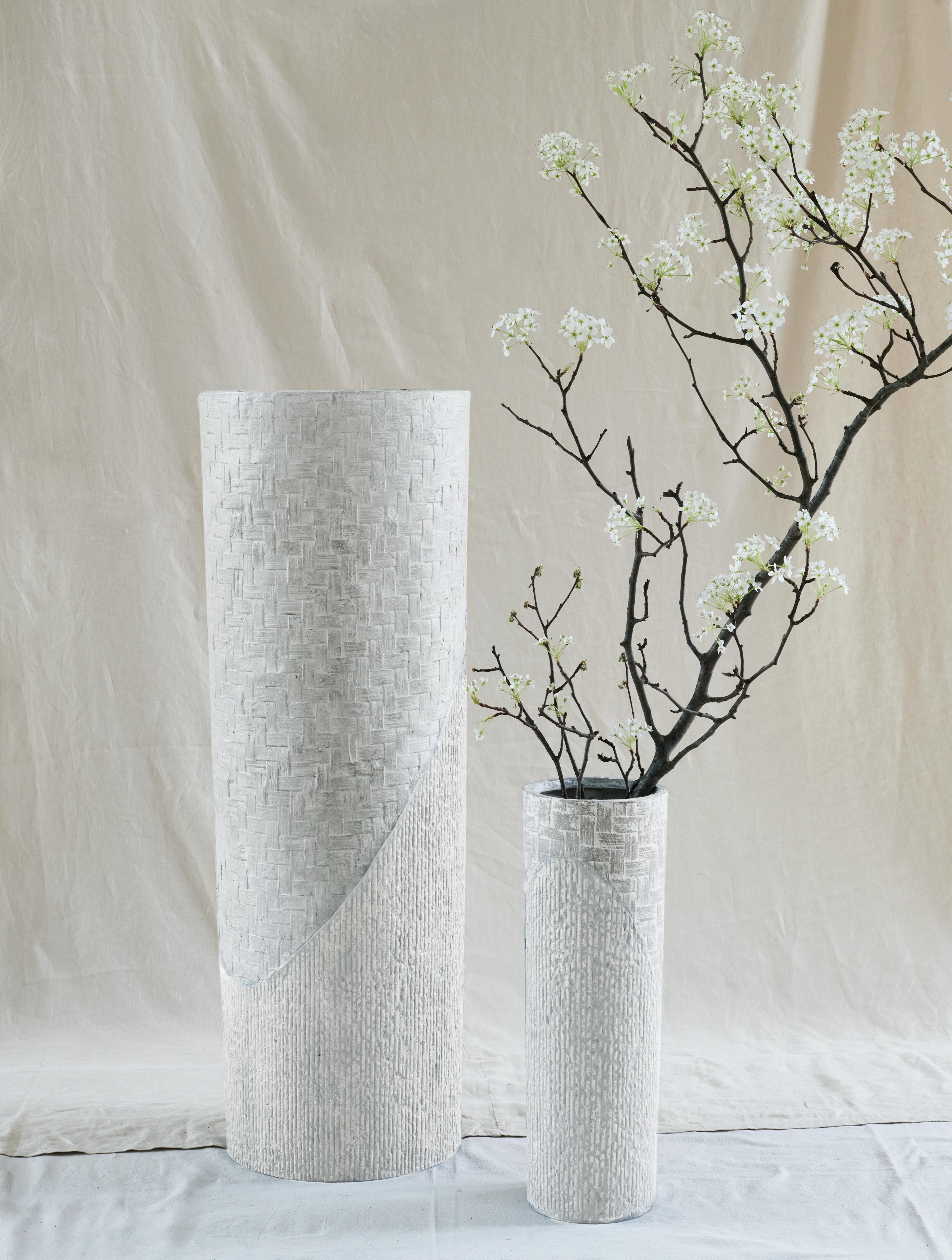 A tall, strikingly elegant cylindrical vessel featuring a subtle two-toned, dual-textured imprint.

For indoor or outdoor use.

15” W x 42.9” H x 15” D
38.1 x 109.2 x 38.1 cm
Materials: STONECAST® Natural Crushed Limestone & NUCAST® Recycled Paper