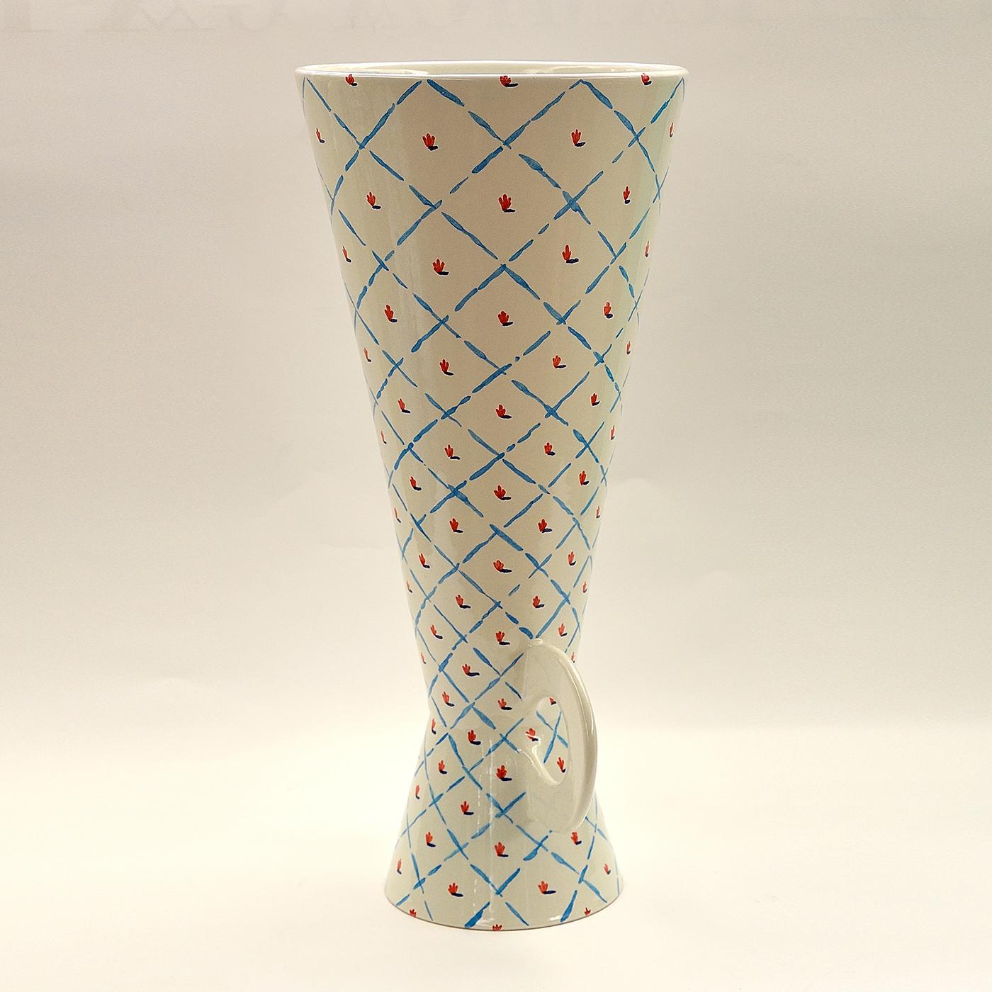 This ceramic vase was made on a lathe and enameled in earthenware. The geometric lines and floral pattern were painted by hand in blue and red over a gleaming white base. This piece is one in a limited series of 6 crafted by Ugo la Pietra.