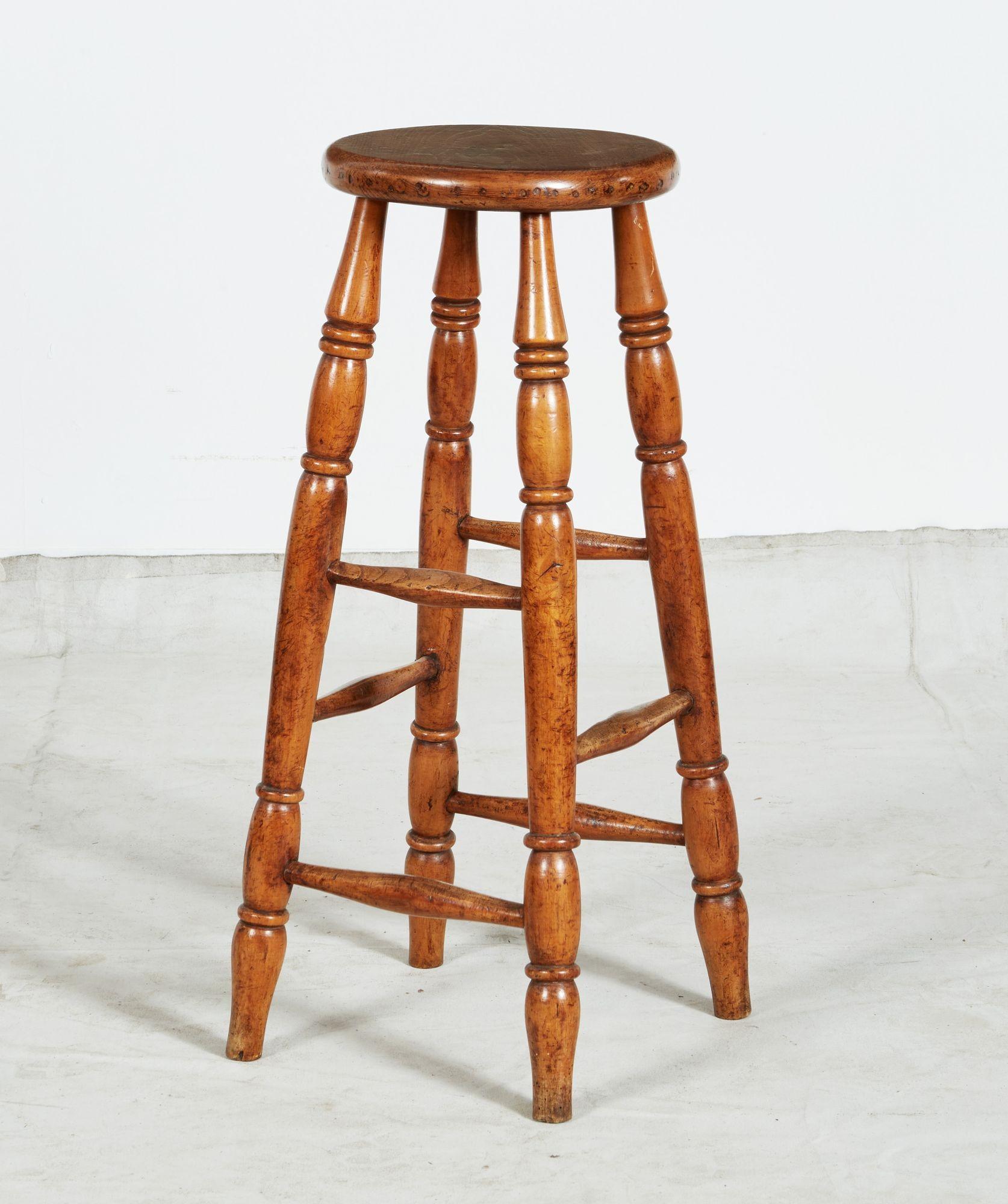 A tall windsor stool with nice patina having circular top over four ring turned legs joined by two tiers of stretchers. Sturdy and attractive. Useful as a bedside table in addition to seating.