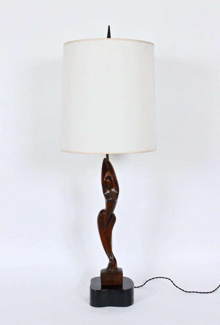 Yasha Heifetz hand-carved mahogany female form table lamp. Handcrafted slim, smooth mahogany figure mounted on free-form black enameled wooden base. Small footprint. 30H to top of socket. 24H to top of figure. Shade shown for display only (15H x 12D