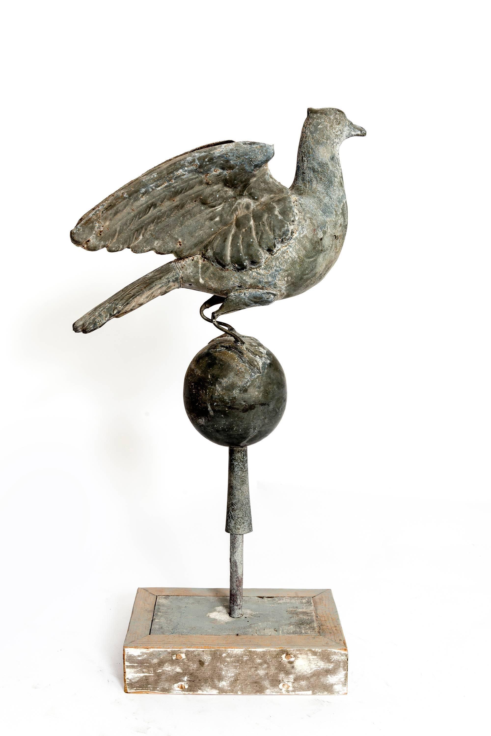 A wonderful rendition of a bird sitting atop and globe and set on a wooden stand. Great detail and patina of this vintage decoration.