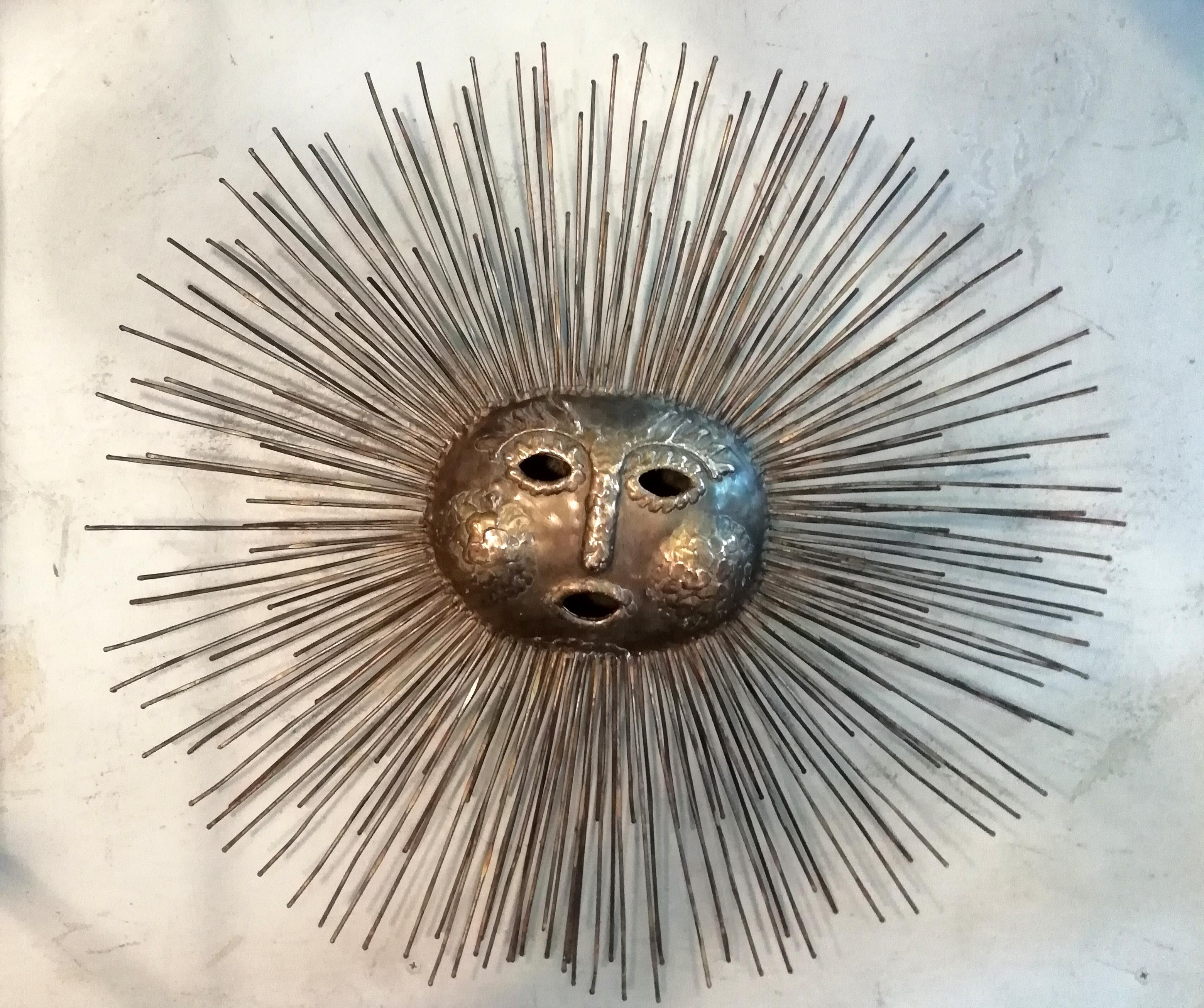 A fine Mexican Mid-Century Modern bronze and brass wall sculpture in shape of a sun by Talleres Emaús in Cuernavaca. The bronze sun shows human face motifs and brass rod rays. Sealed on back.

A removable shank for table base included.