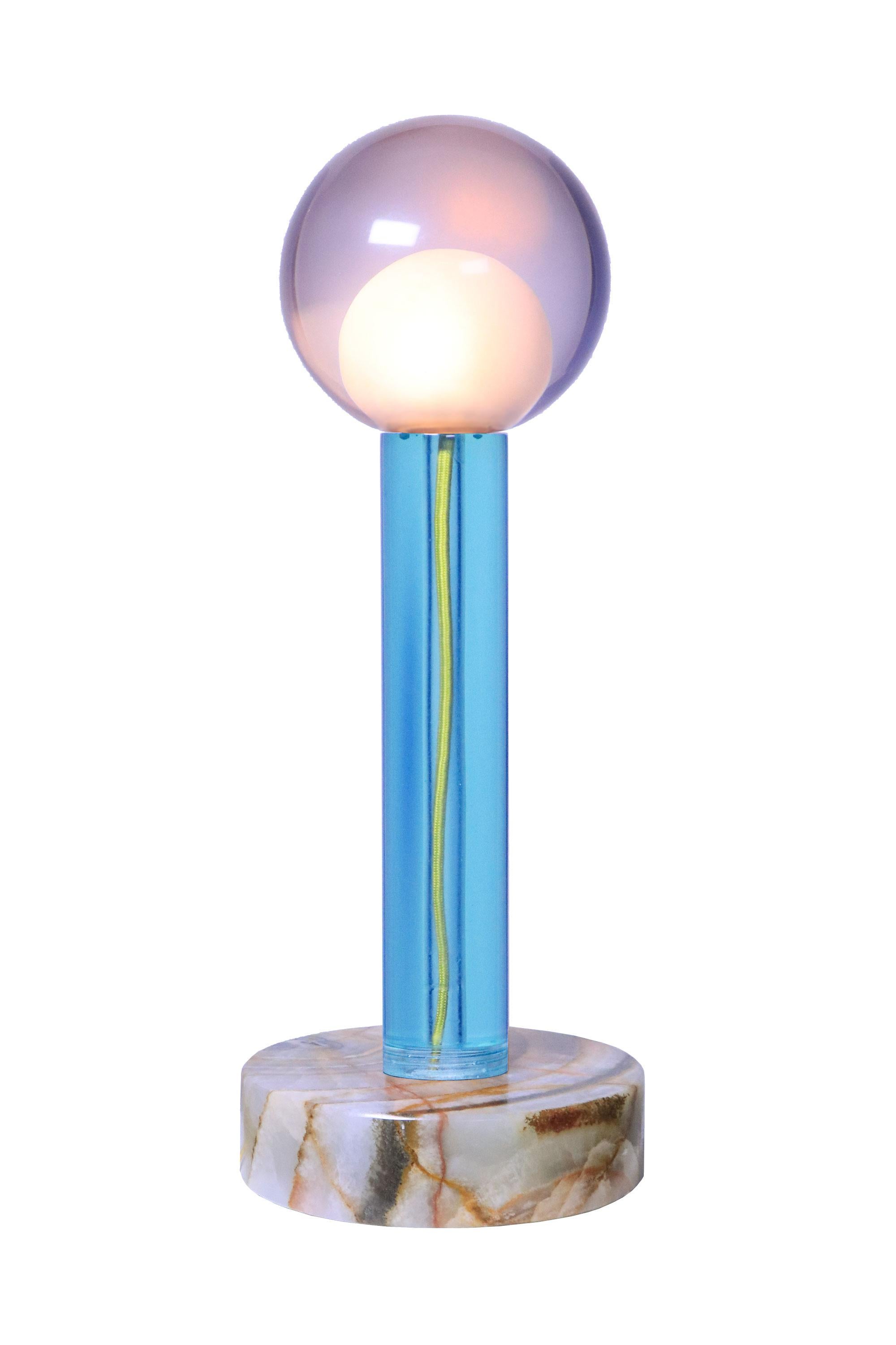 Inspired by the flower's thallus, the main body unveils the cable that brings energy to the bulb crowned at the top. The pedestal is sculpted in Mexican onyx. Due to craftsmanship of the resin and the infinite colored veins of the onyx, each piece