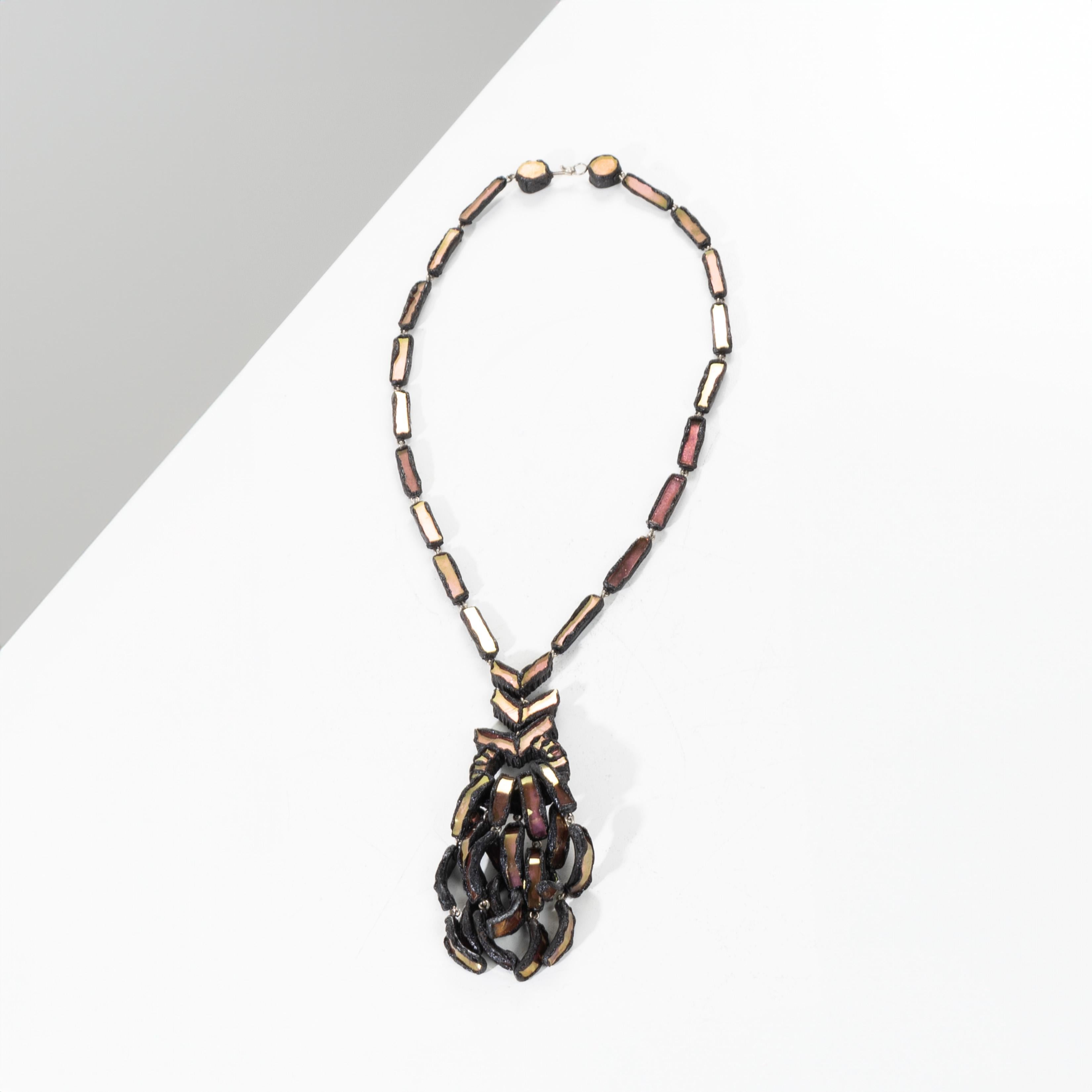 Talosel long necklace inlaid with pink mirrors by Line Vautrin.
As a pendant, three “arrows” supporting a ring on which tassels hang.
The clasp fixed on two pellets.
One of the Talosel elements bearing the “JOUX” stamp
Very good condition