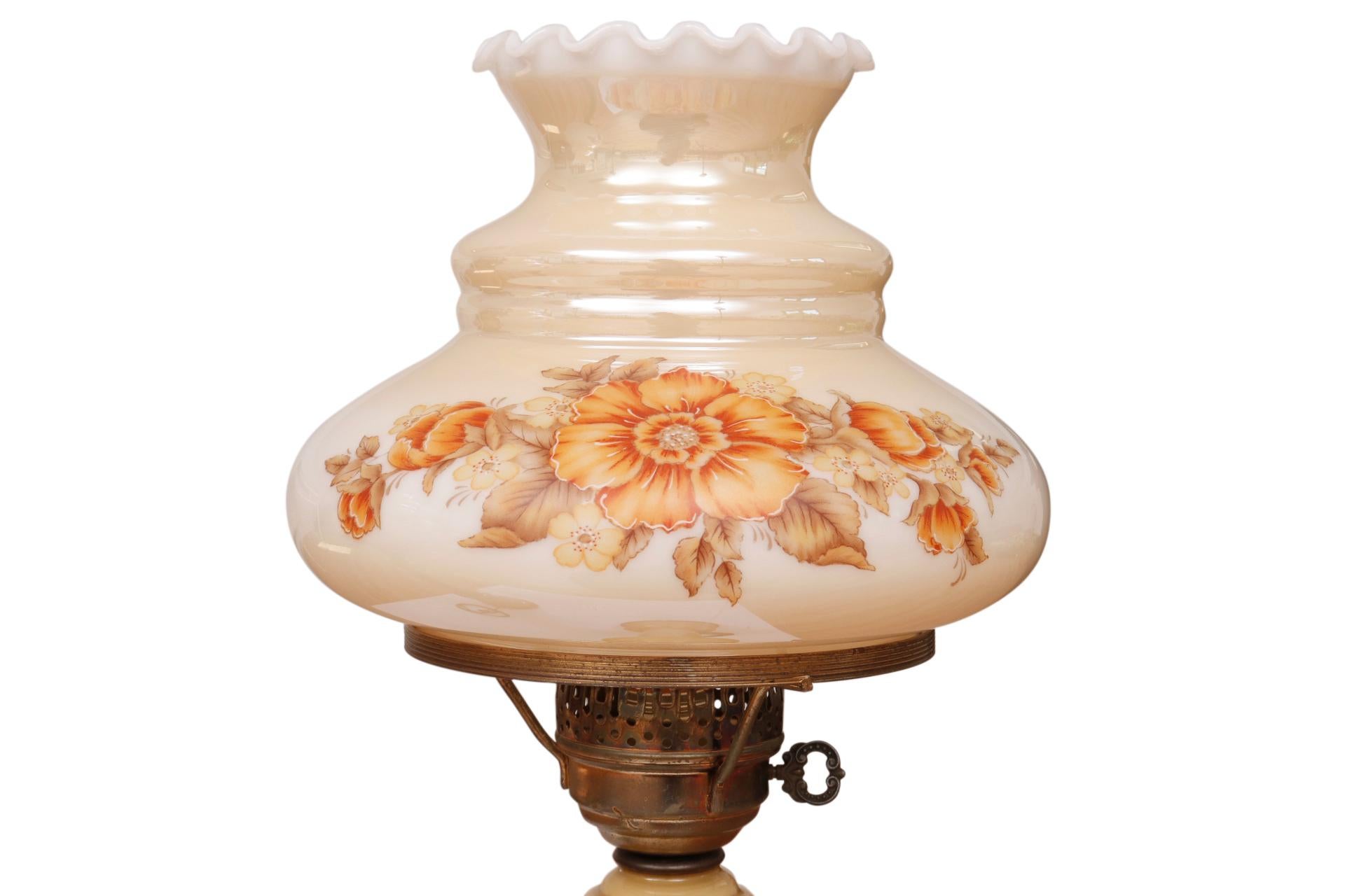 A pair of traditional table lamps made of glass, painted on the interior in a soft caramel color. Glass shades called Tam-o-Shanters, named after the Scottish bonnet worn by men, are painted with a floral motif in orange tones. Each lamp measures