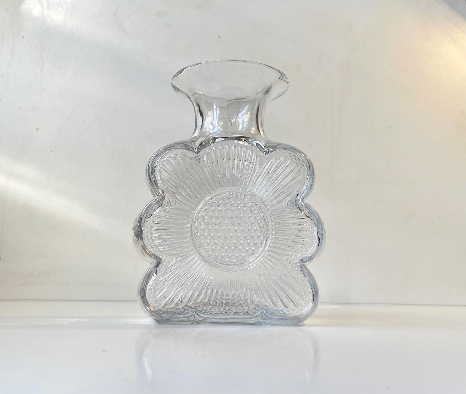 Vase en verre transparent avec motif de tournesol sur les deux côtés. Il s'appelle Amuletti Kinkas et a été conçu par Tamara Aladin et fabriqué par Riihimäen Lasi en Finlande dans les années 1960 ou au début des années 1970. Mesures : H : 20 cm, L/D