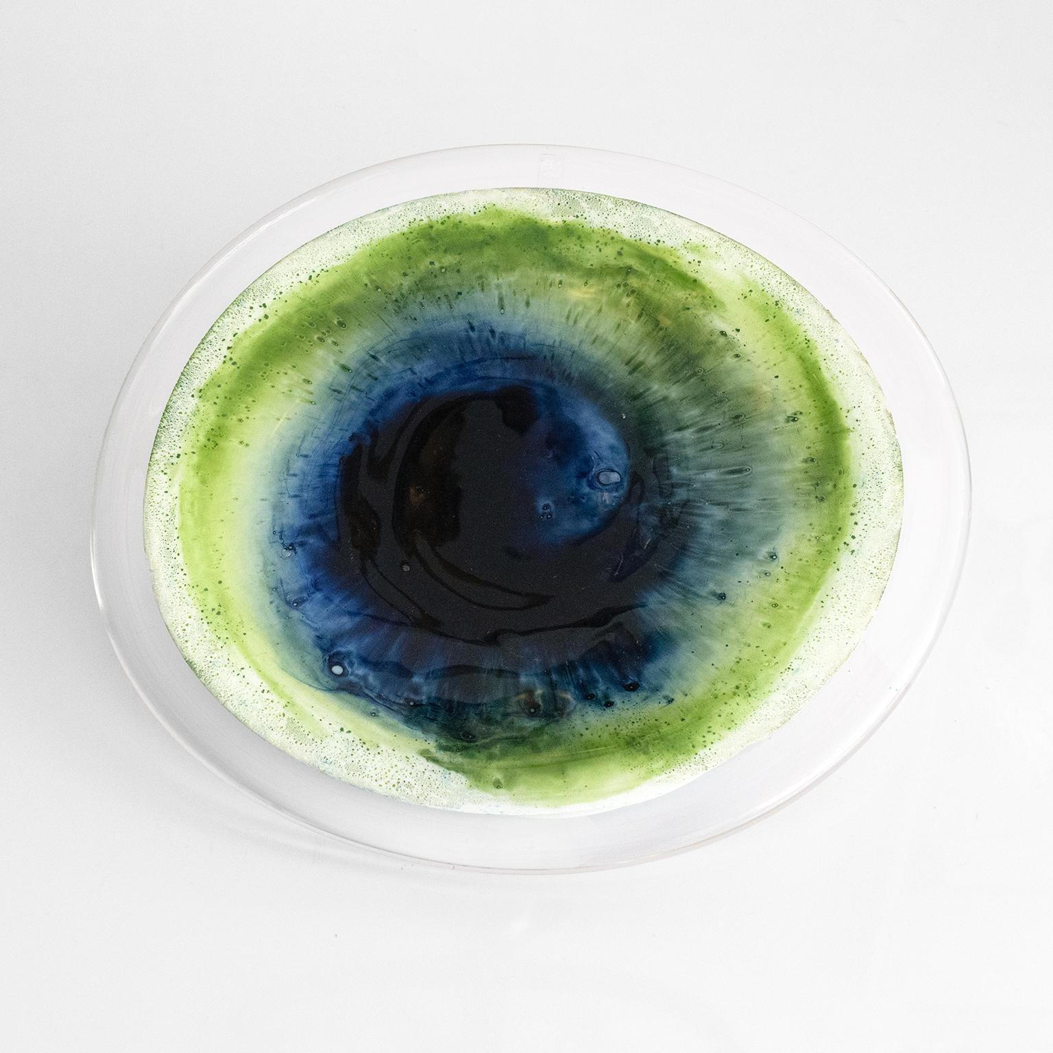 A bold, vibrant glass “Koralli” dish designed by Tamara Aladin for Riihimäen Lasi Oy. The deep blue and green colored glass swirl in a clear glass body resting on an opaque white base. Made in Riihimäki, Finland 1970. 

Dimensions: 14” x 16”,