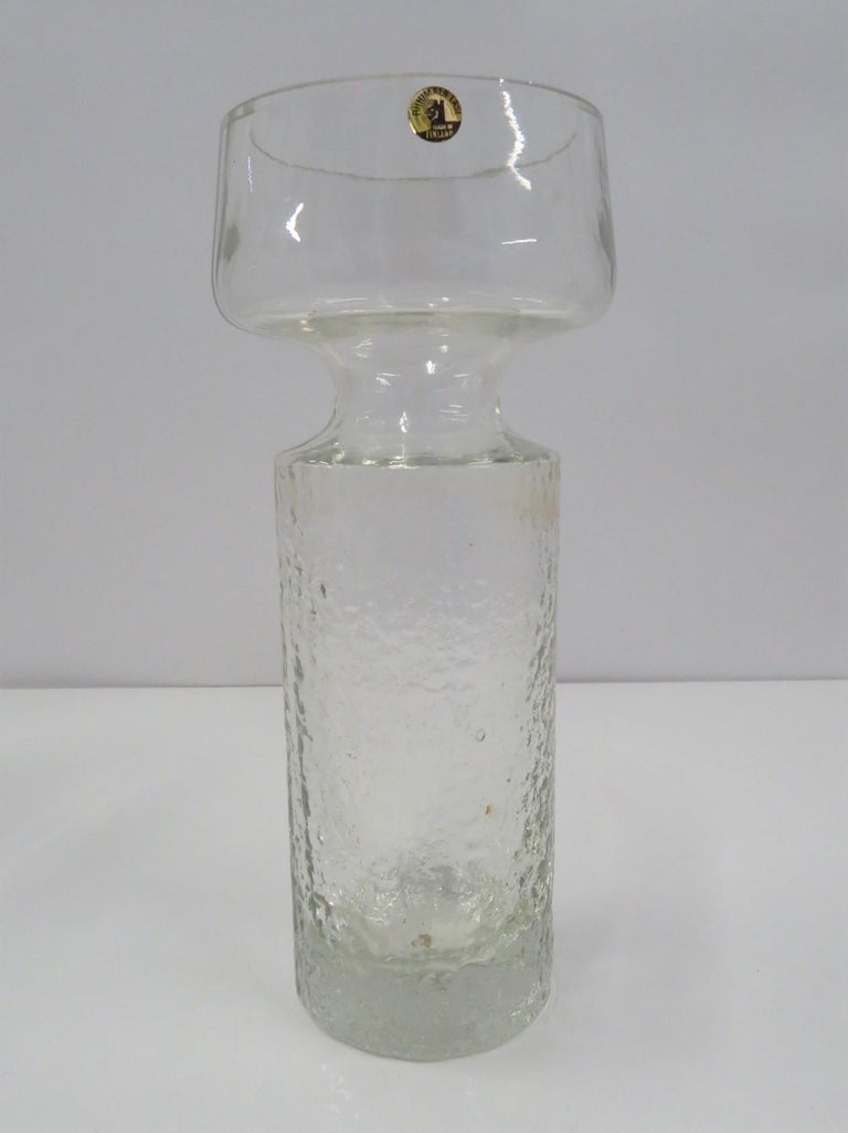 A stunning mold blown glass Safari Vase by Tamara Aladin for Riihimäen Lasi Oy or Riihimaki of Finland. Textured bottom to the shoulder and then clear on top.
Nice and heavy clear glass Vase model # 1495 was produced from 1968 to 1974. In very good