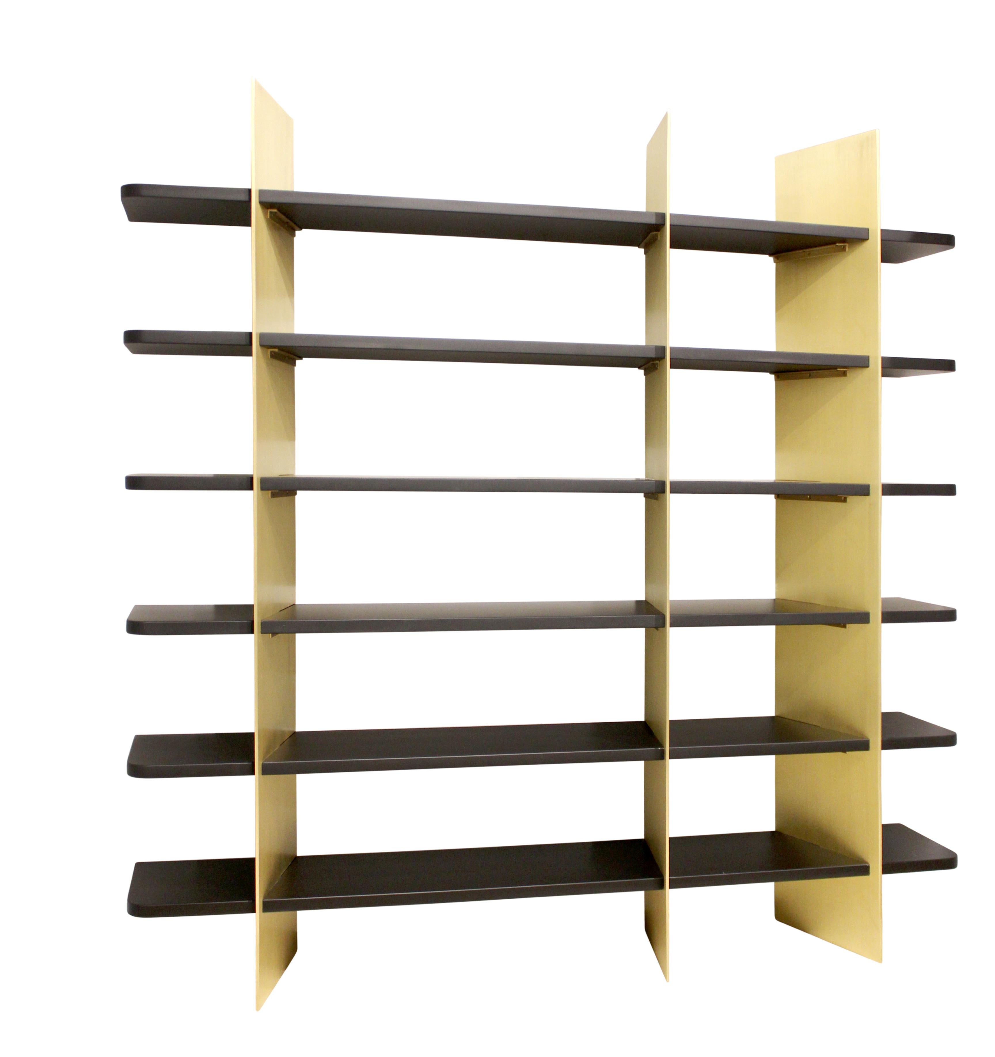 Dramatic brass and matte lacquered wood bookcase. Slotted wood and metal components fit together to form a shelving unit of striking contrast. Custom sizes, materials, and finishes available.
