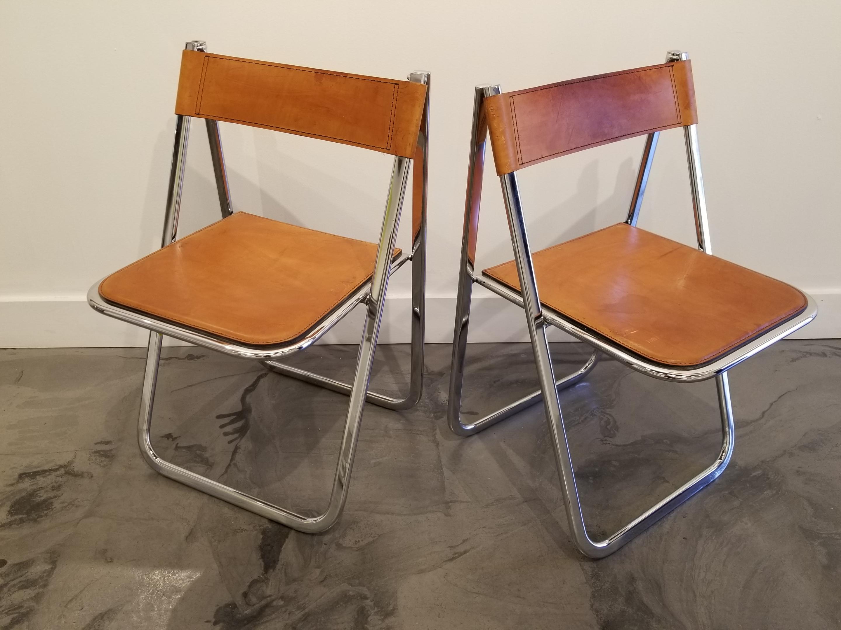 A pair of chrome and leather folding dining chairs by Arrben, Italy, circa 1970s. Makers mark impressed in leather seat and cast into chrome frame. Chrome frames in excellent vintage condition, caramel color leather has beautiful patina.