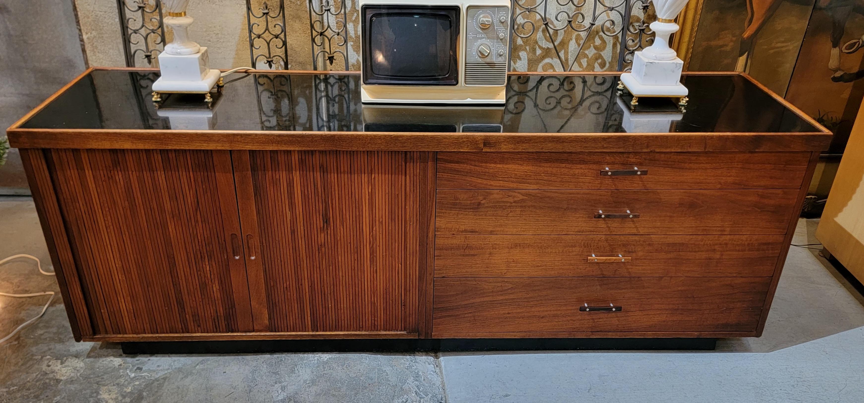 A fine Mid-Century Modern, Glenn of California, tambour door credenza. Features 2 sliding tambour doors and 4 drawers. Black glass top insert. (waterproof top word work well as a bar or cocktail cabinet). All wood construction with dovetail drawers.